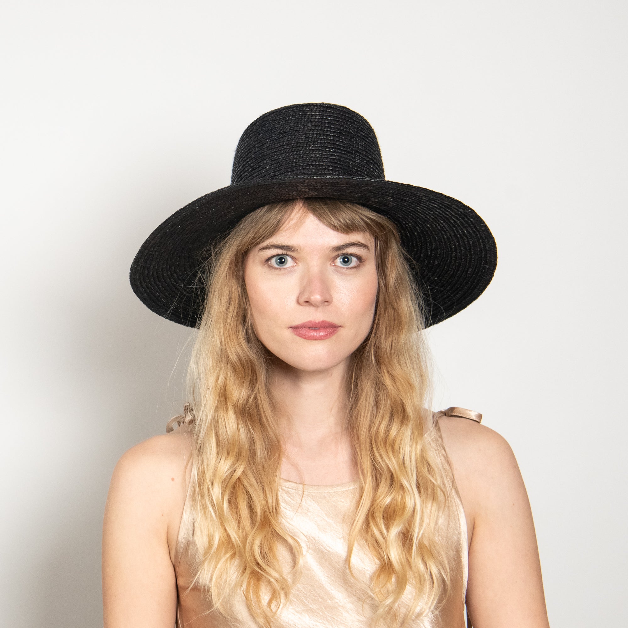 Woman wearing a black hat against a plain background
