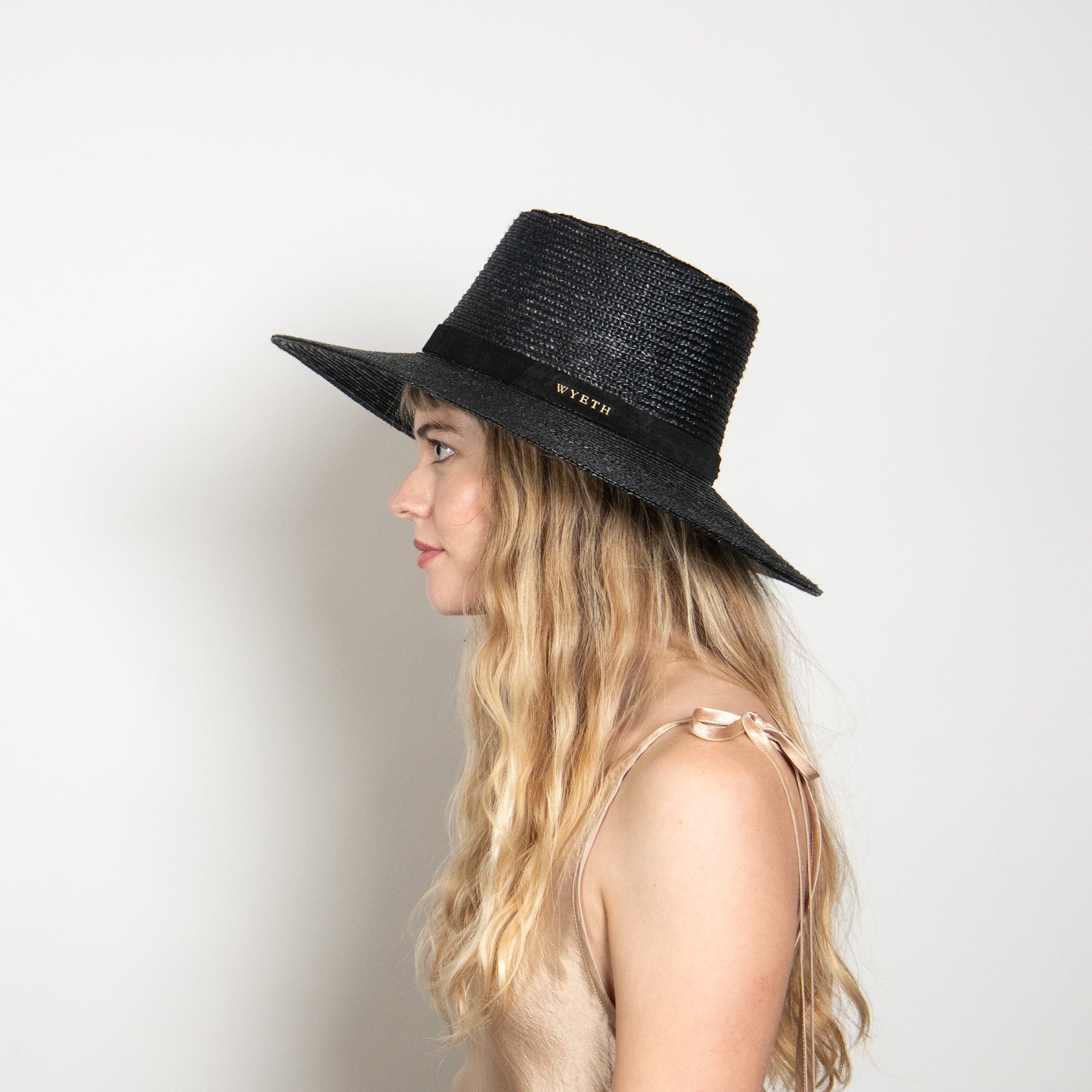Woman wearing a black fedora hat on a white background