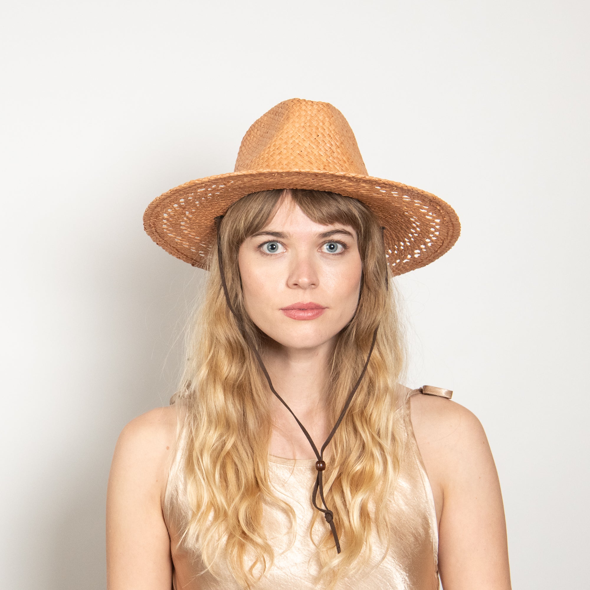 Woman wearing a straw hat against a plain background