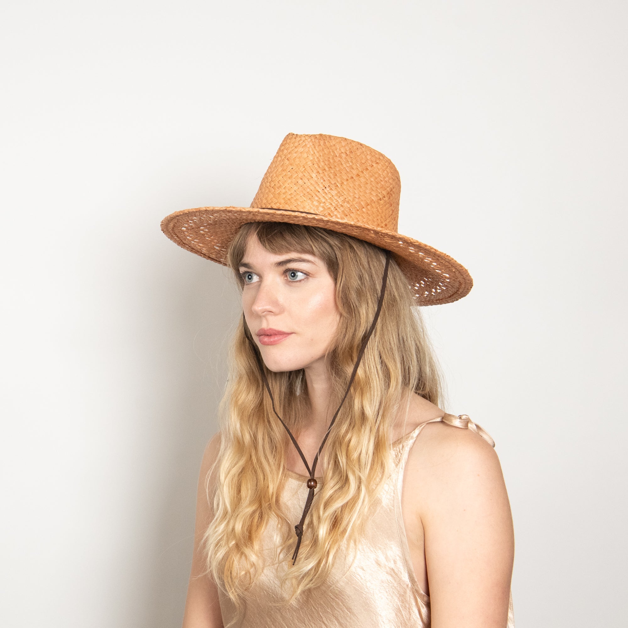 Woman wearing a straw hat against a plain background