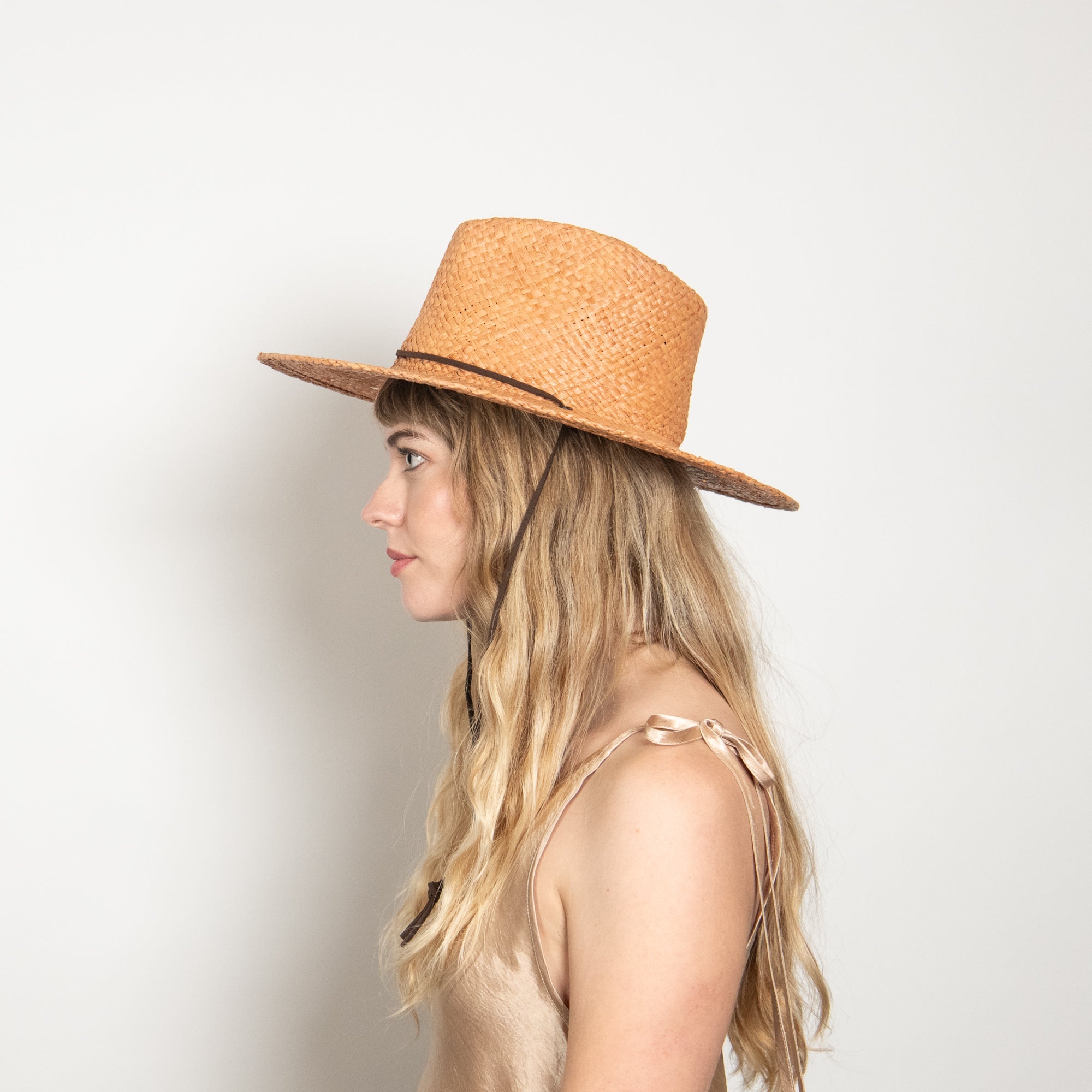 Woman wearing a straw hat against a plain background