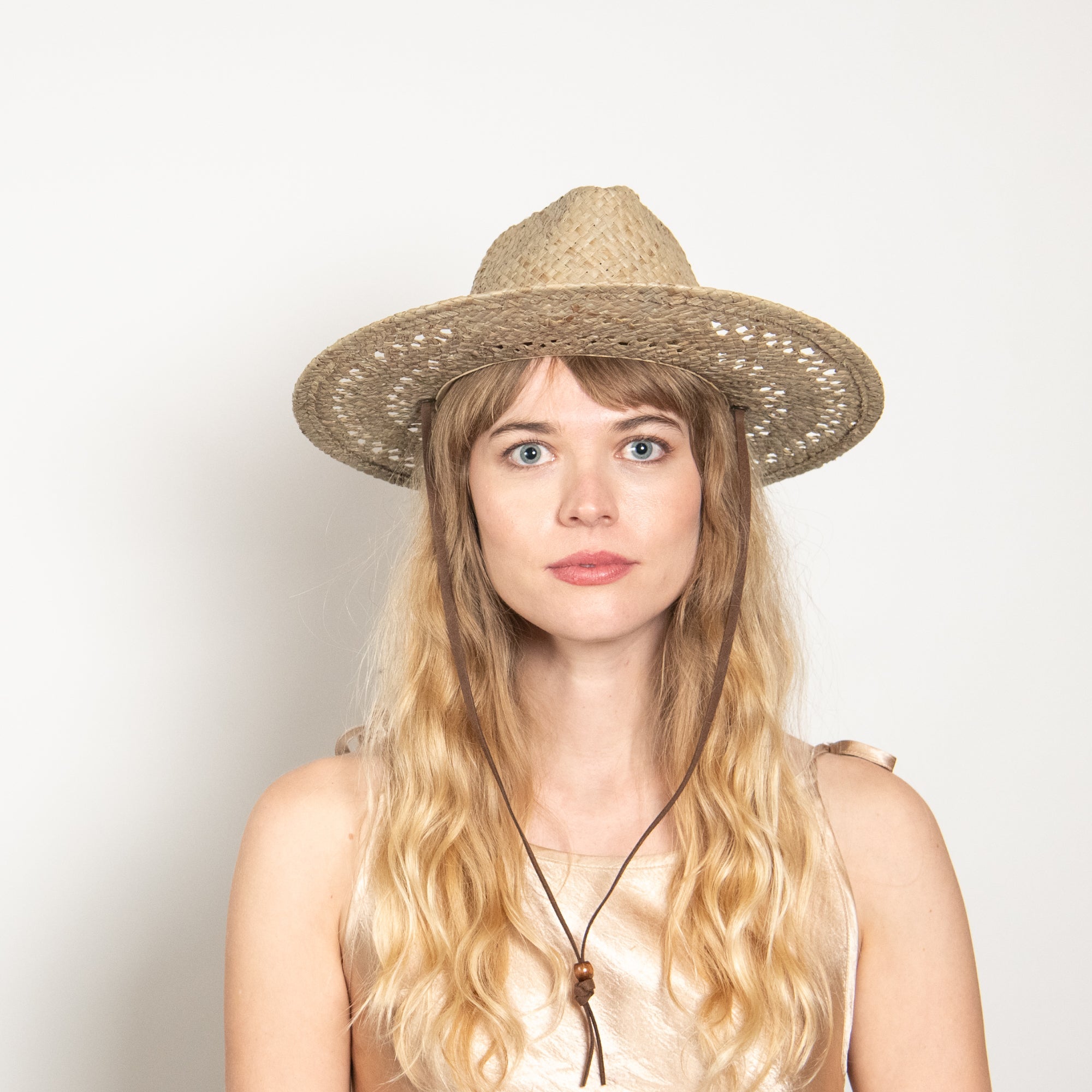 Woman wearing a straw hat against a plain background