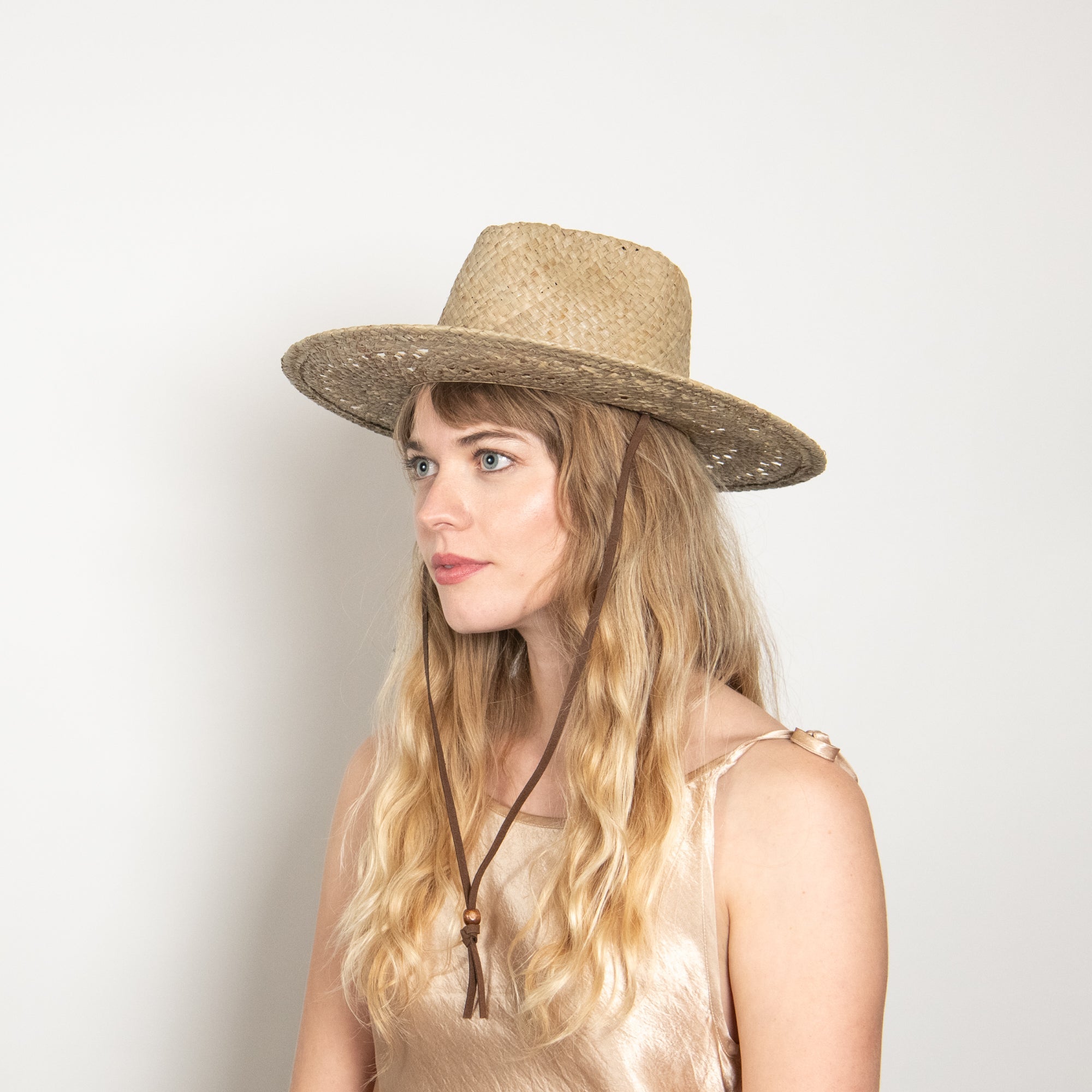 Woman wearing a straw hat against a plain background