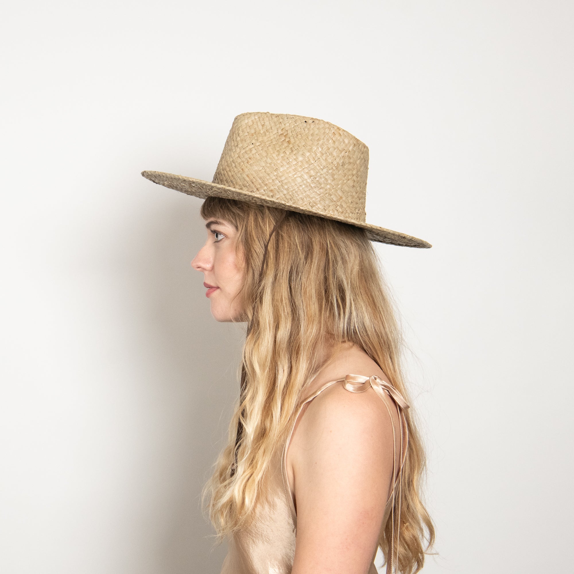 Woman wearing a straw hat against a plain background