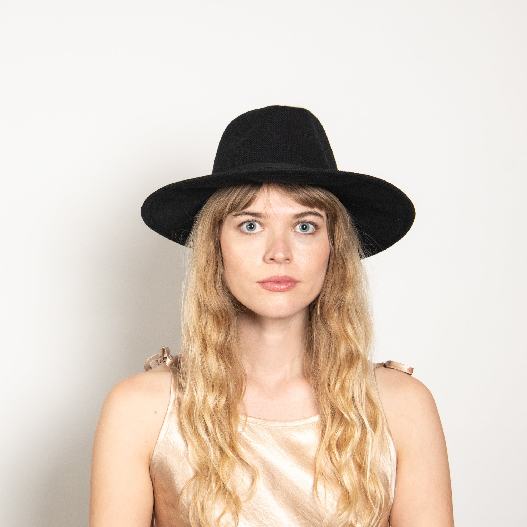 Woman wearing a black hat against a plain background
