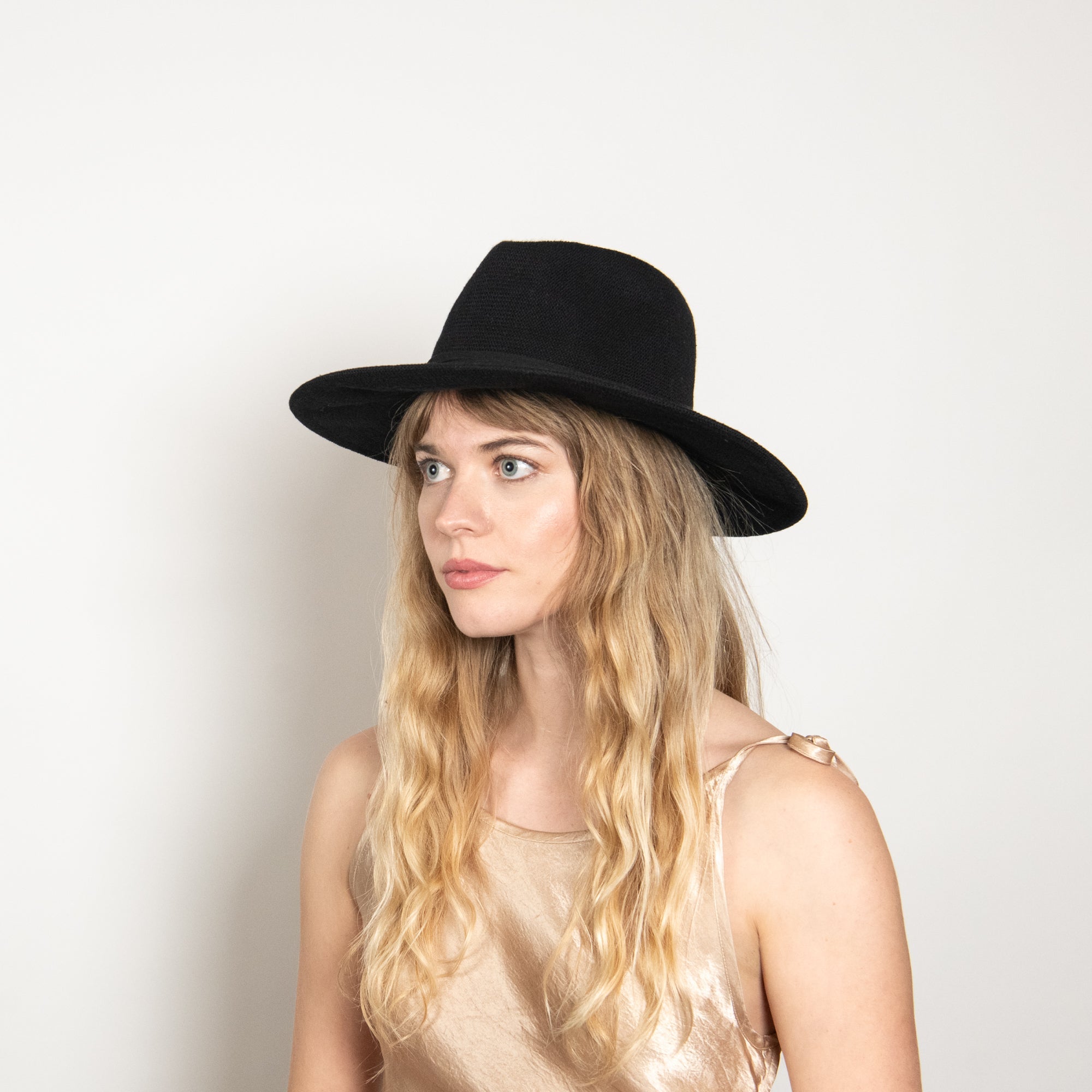 Woman wearing a black hat against a plain background