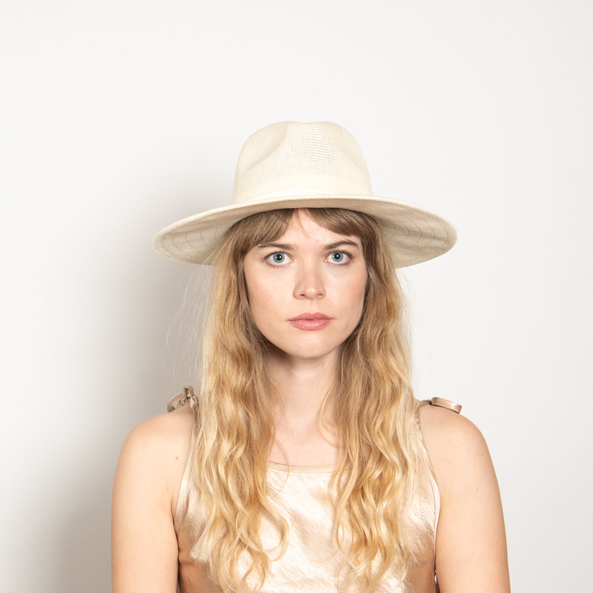 Woman wearing a beige hat against a plain background