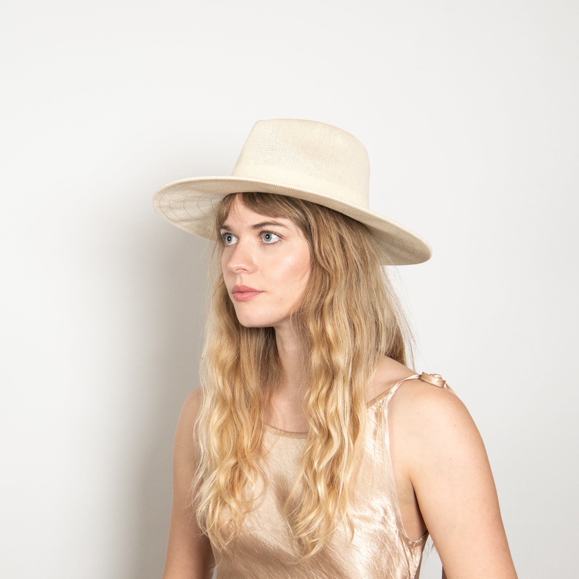 Woman wearing a beige hat against a plain background