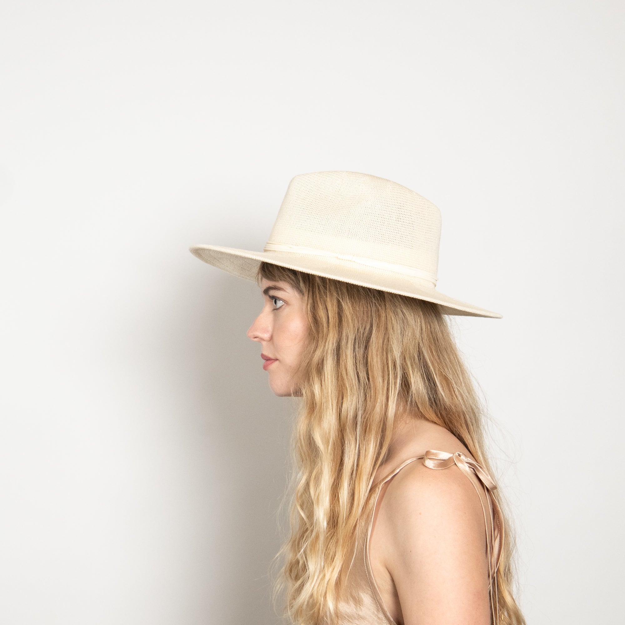 Woman wearing a beige hat against a plain background