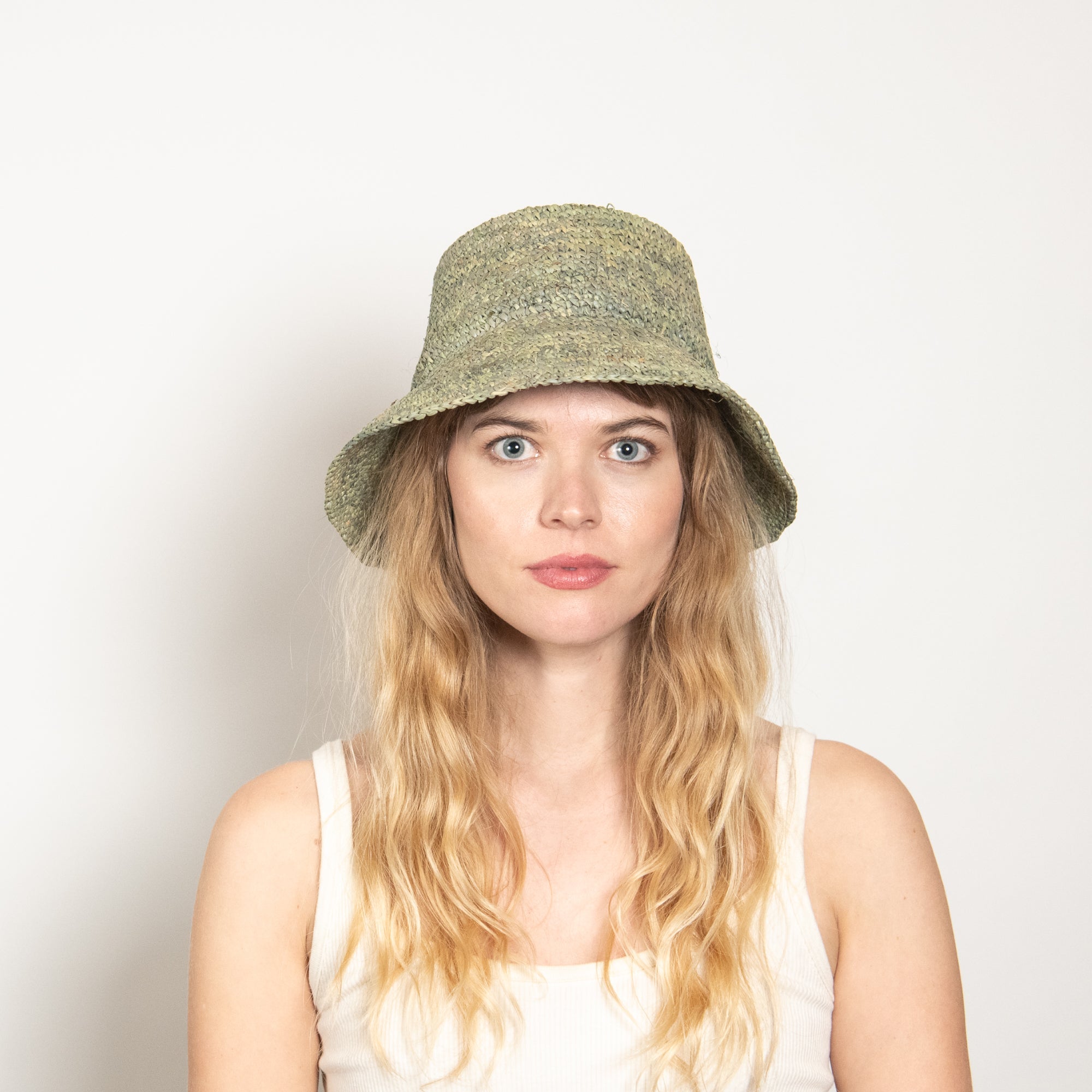 Woman wearing a green bucket hat against a plain background