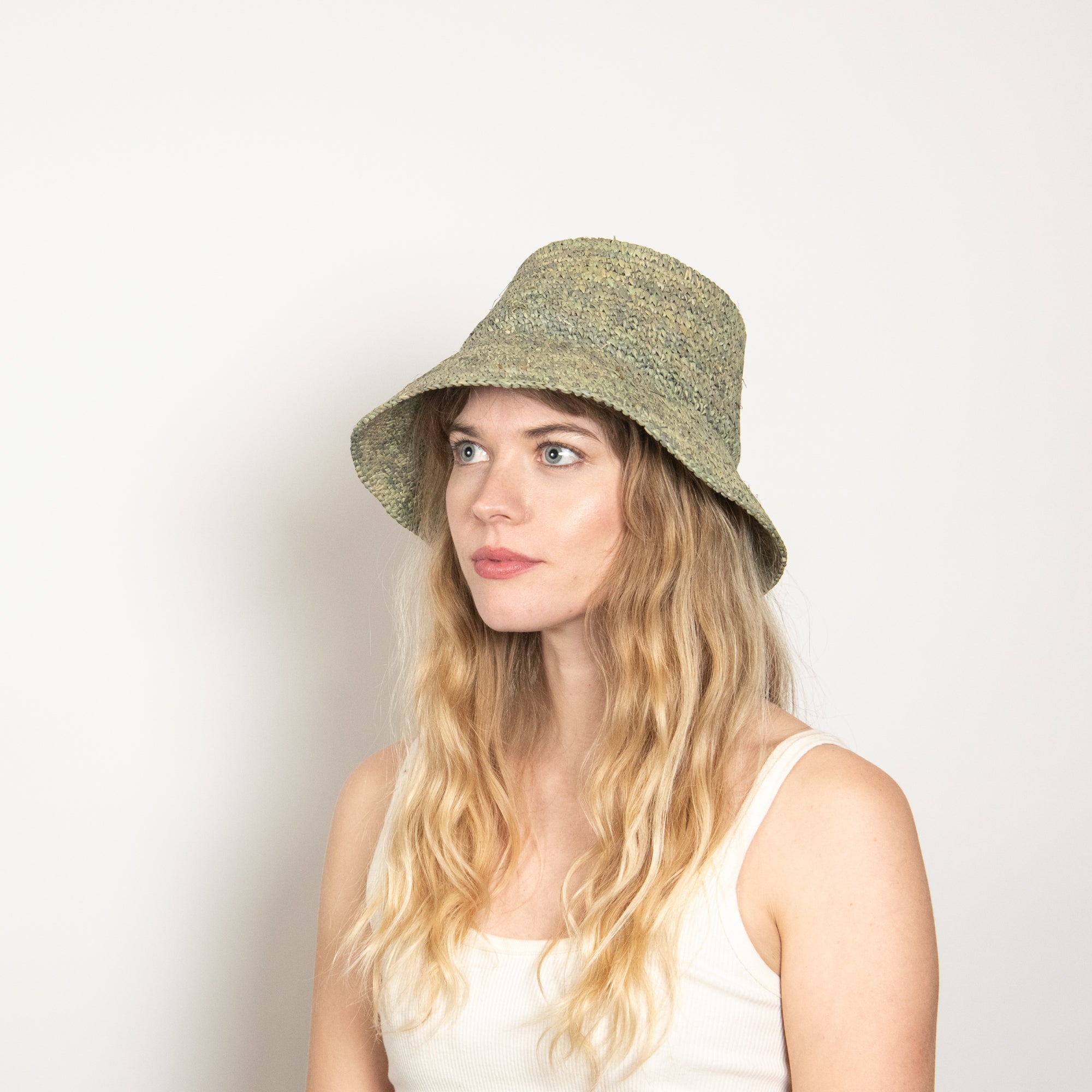 Woman wearing a green bucket hat against a plain background
