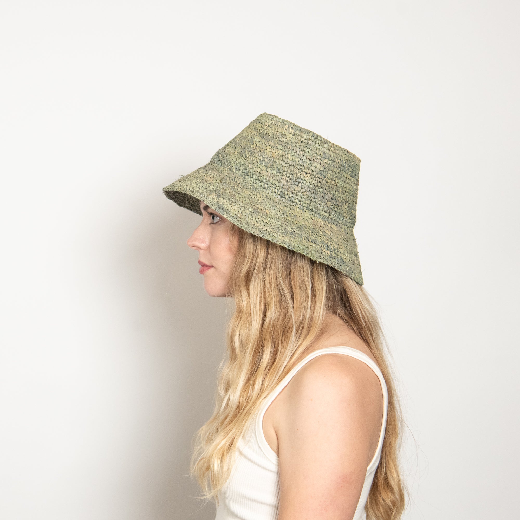 Woman wearing a green bucket hat against a plain background