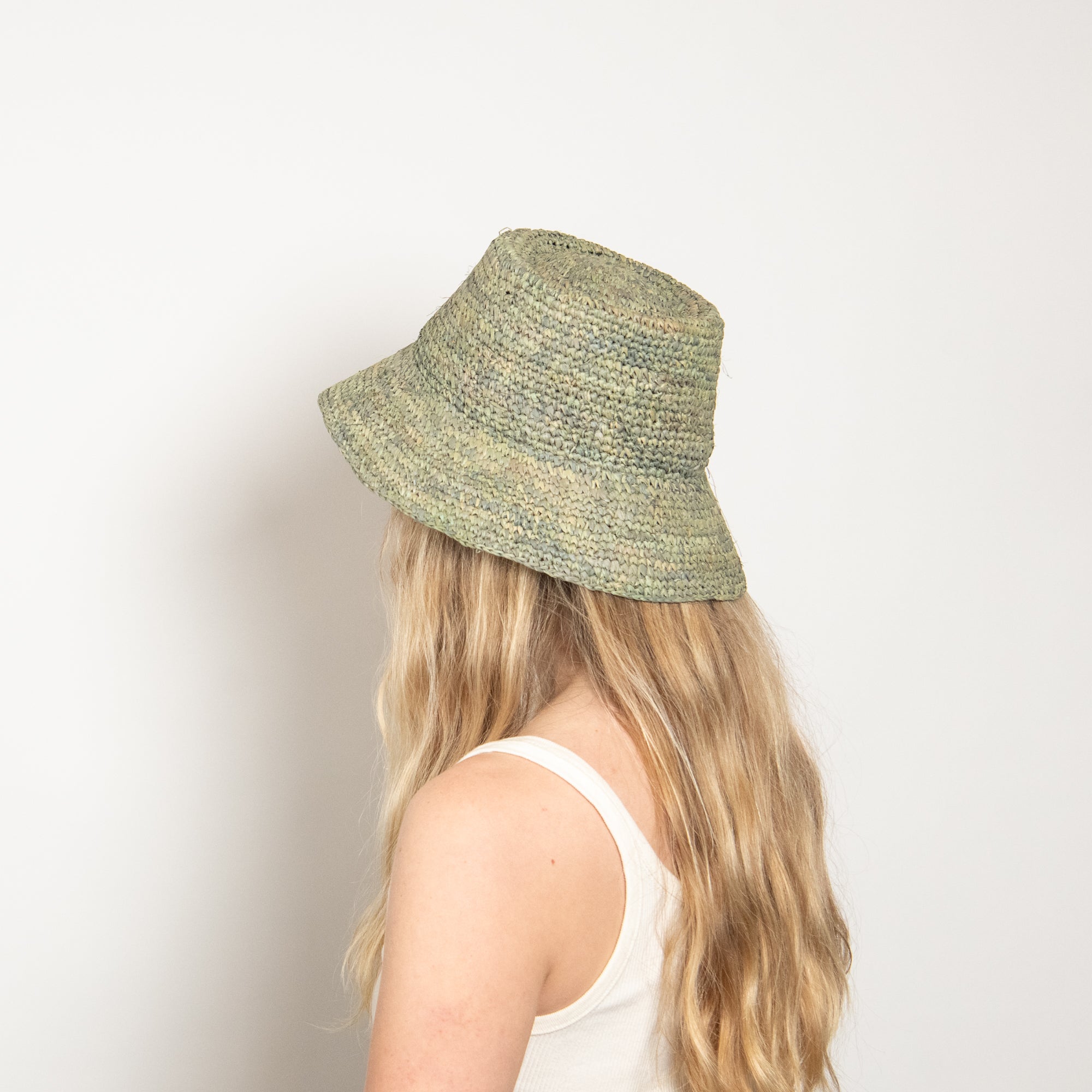 Person wearing a green woven hat against a plain background