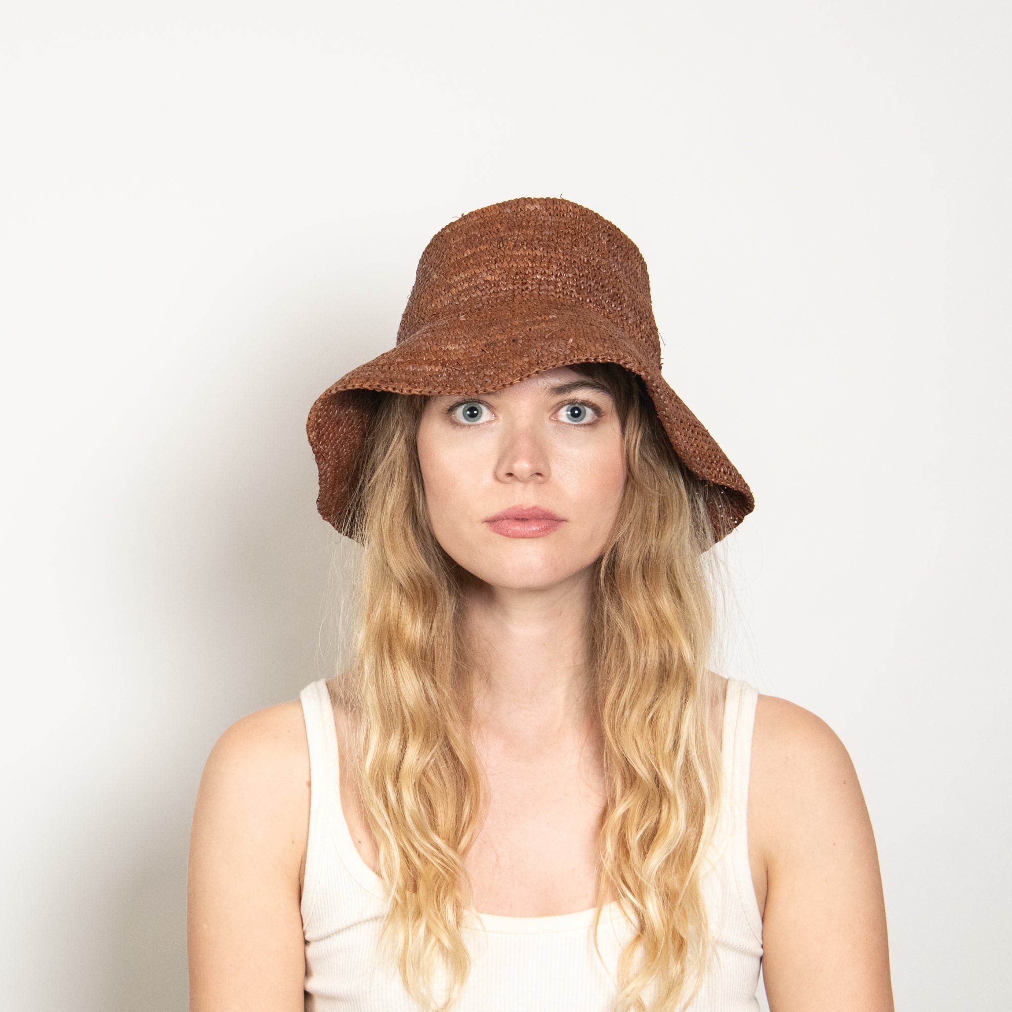 Woman wearing a brown bucket hat against a plain background