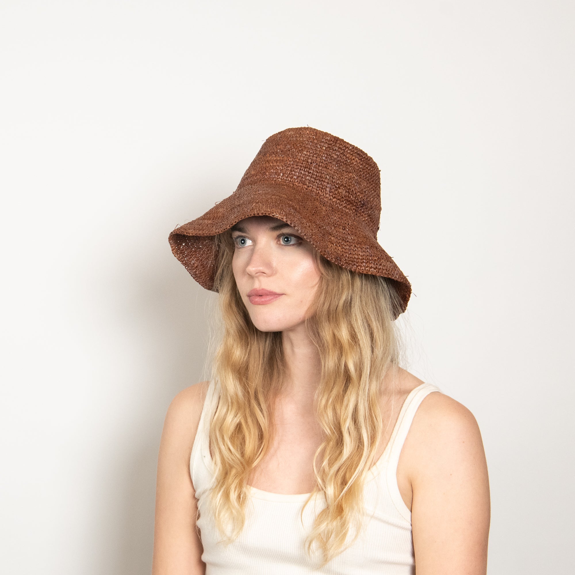 Woman wearing a brown bucket hat against a plain background