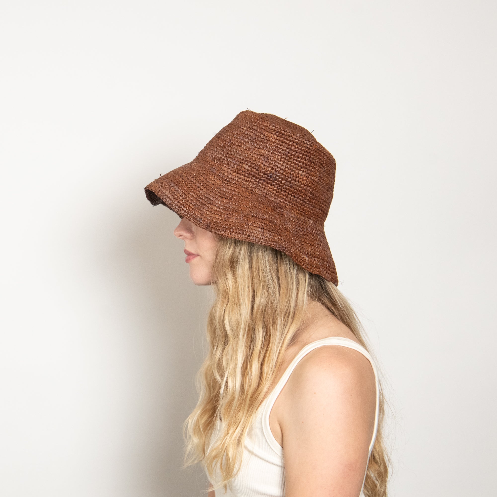 Person wearing a brown woven hat against a white background