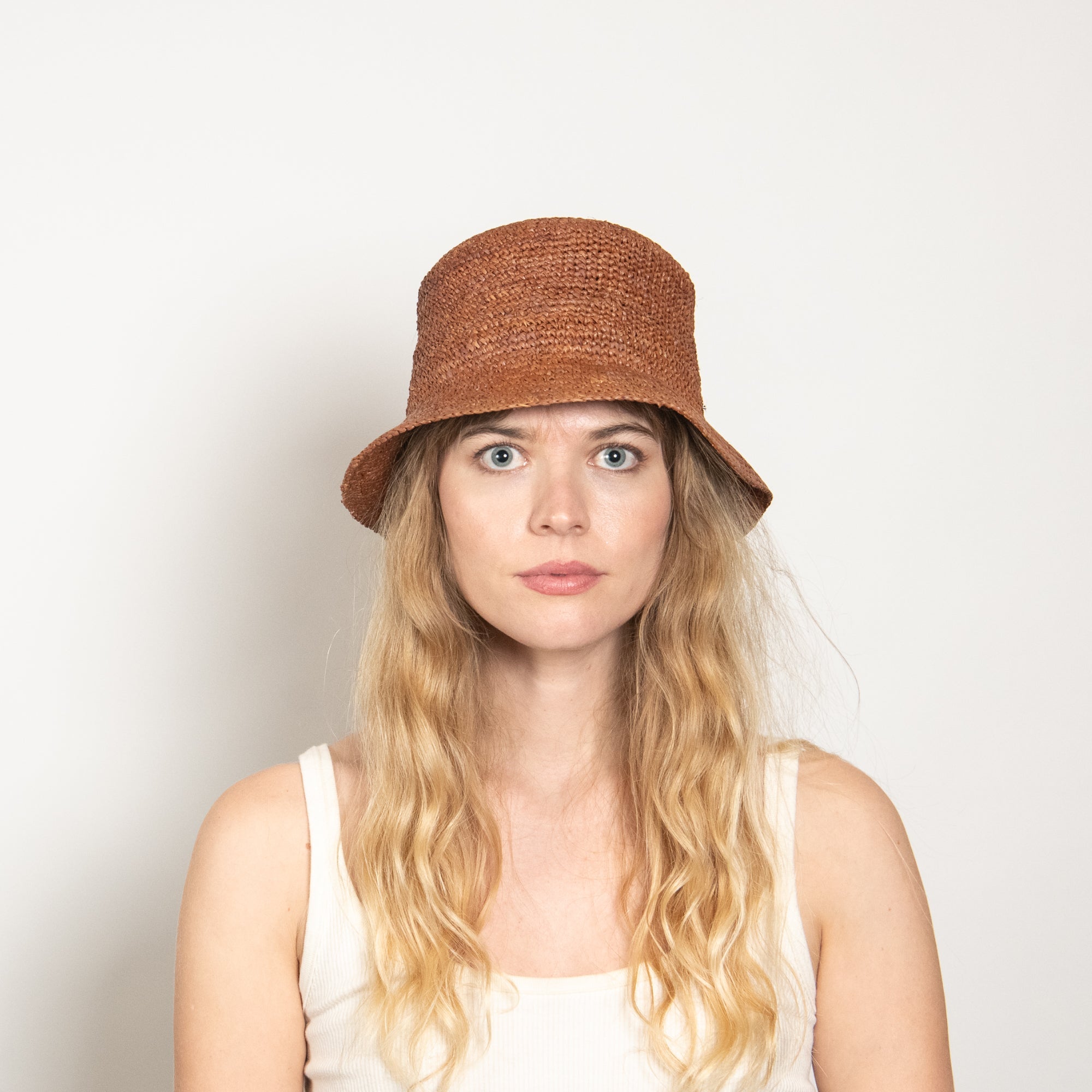 Woman wearing a brown bucket hat against a plain background