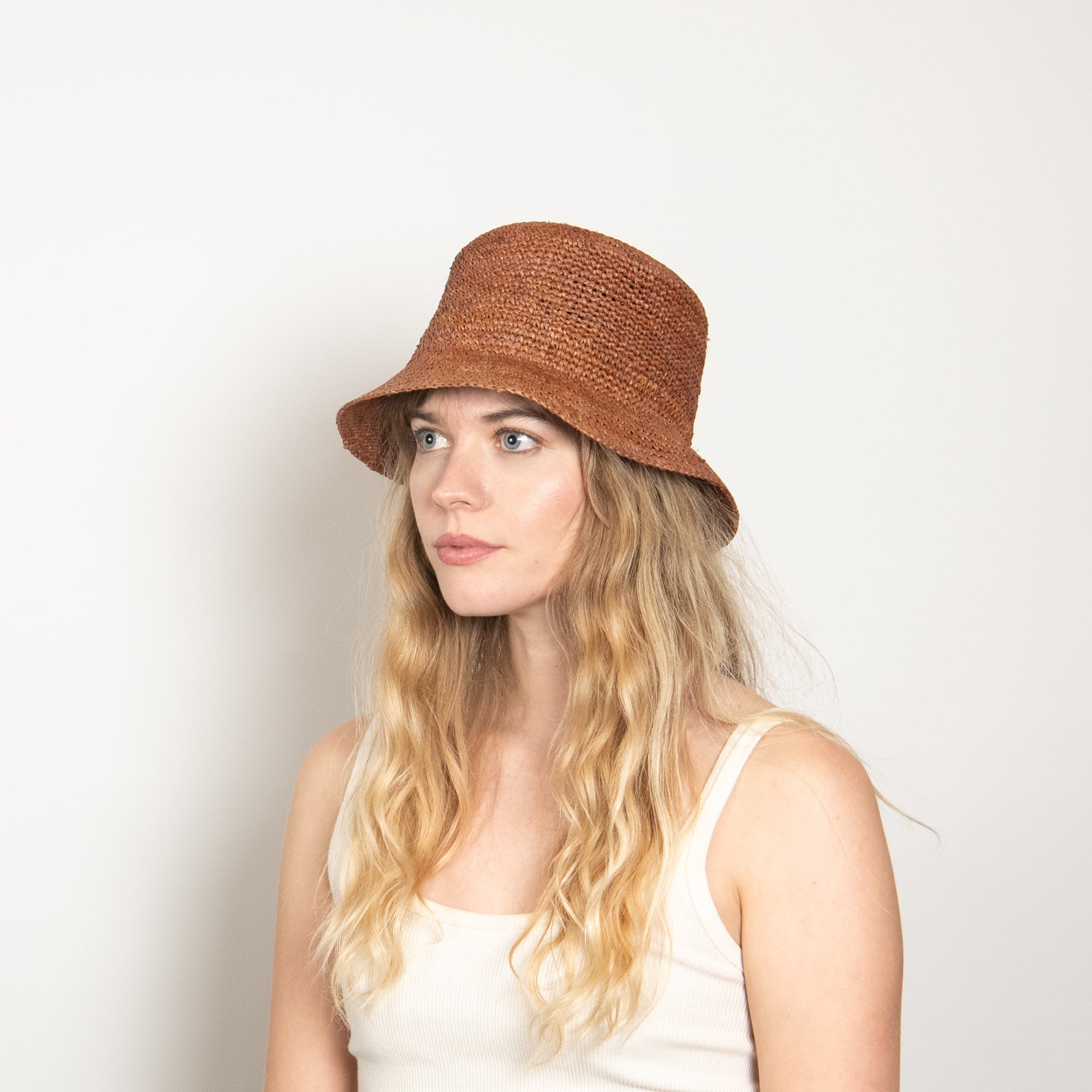 Woman wearing a brown bucket hat against a plain background