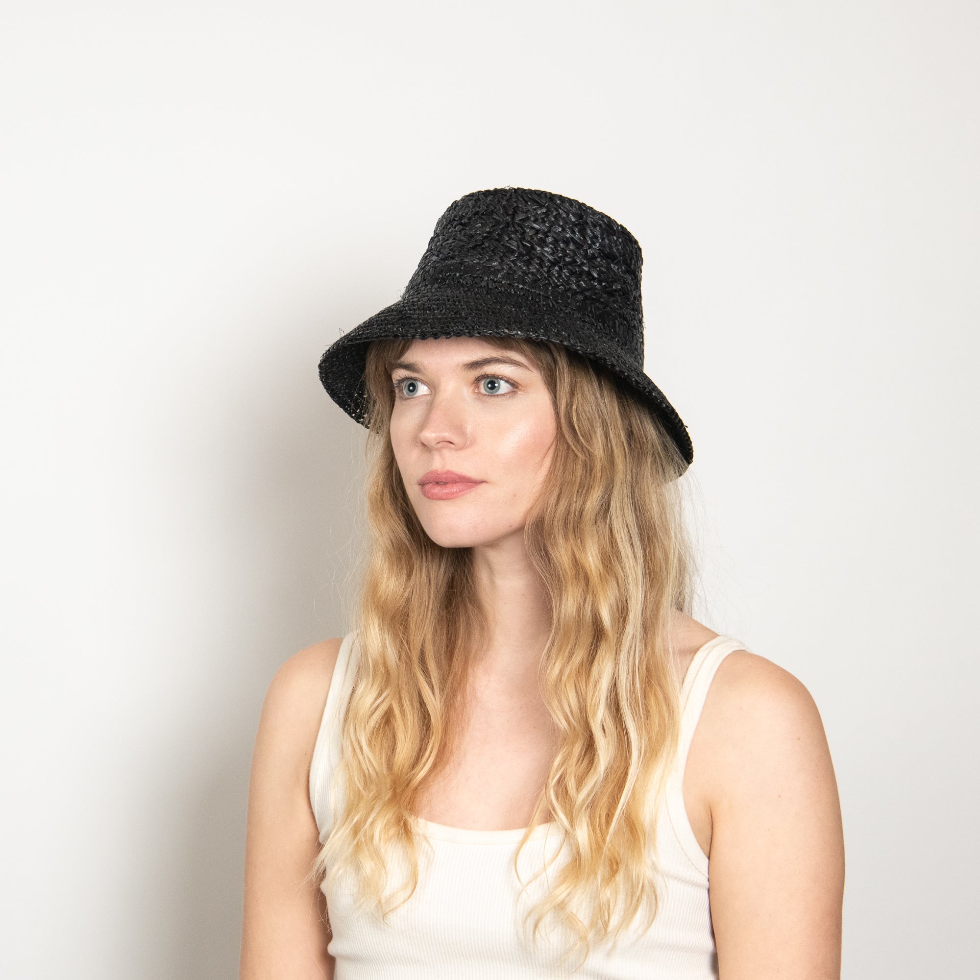 Woman wearing a black textured hat against a plain background