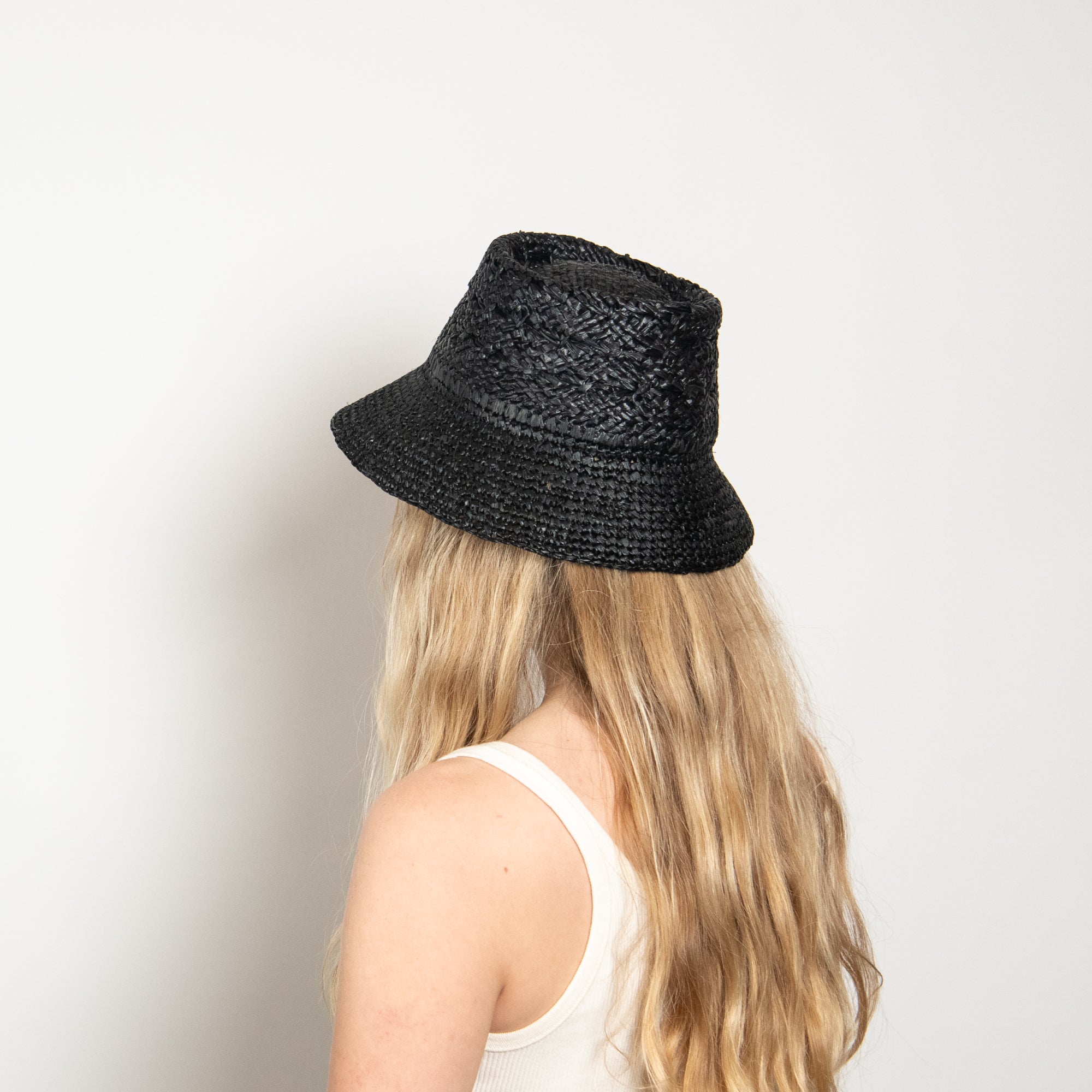 Person wearing a black woven hat against a plain background