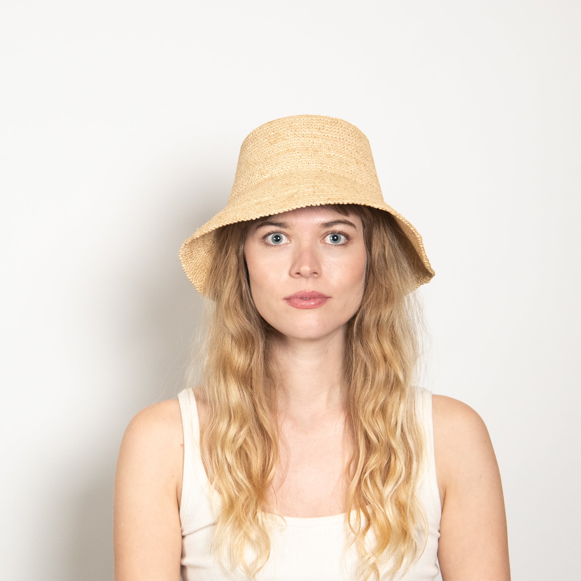 Woman wearing a straw hat against a plain background