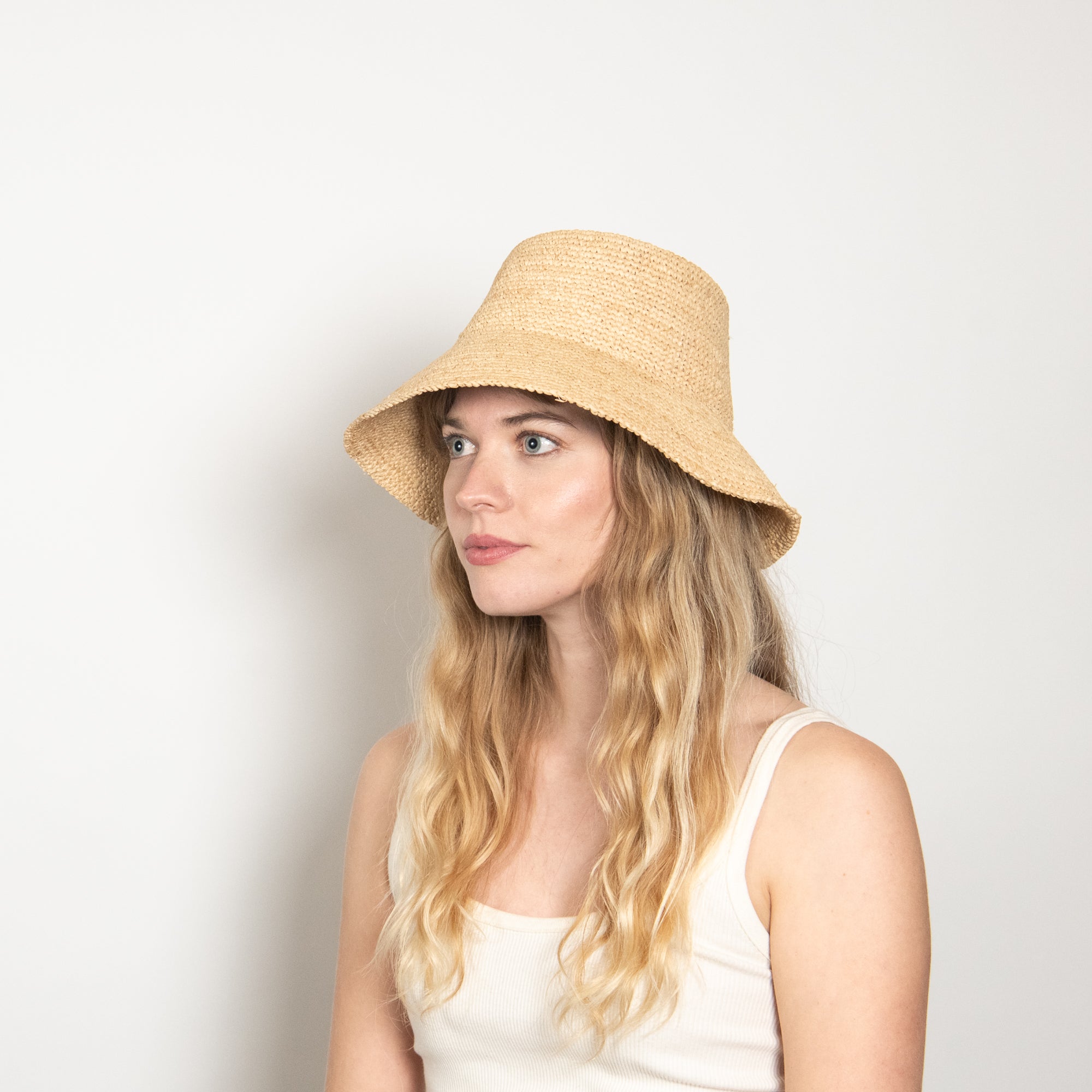 Woman wearing a straw hat against a plain background