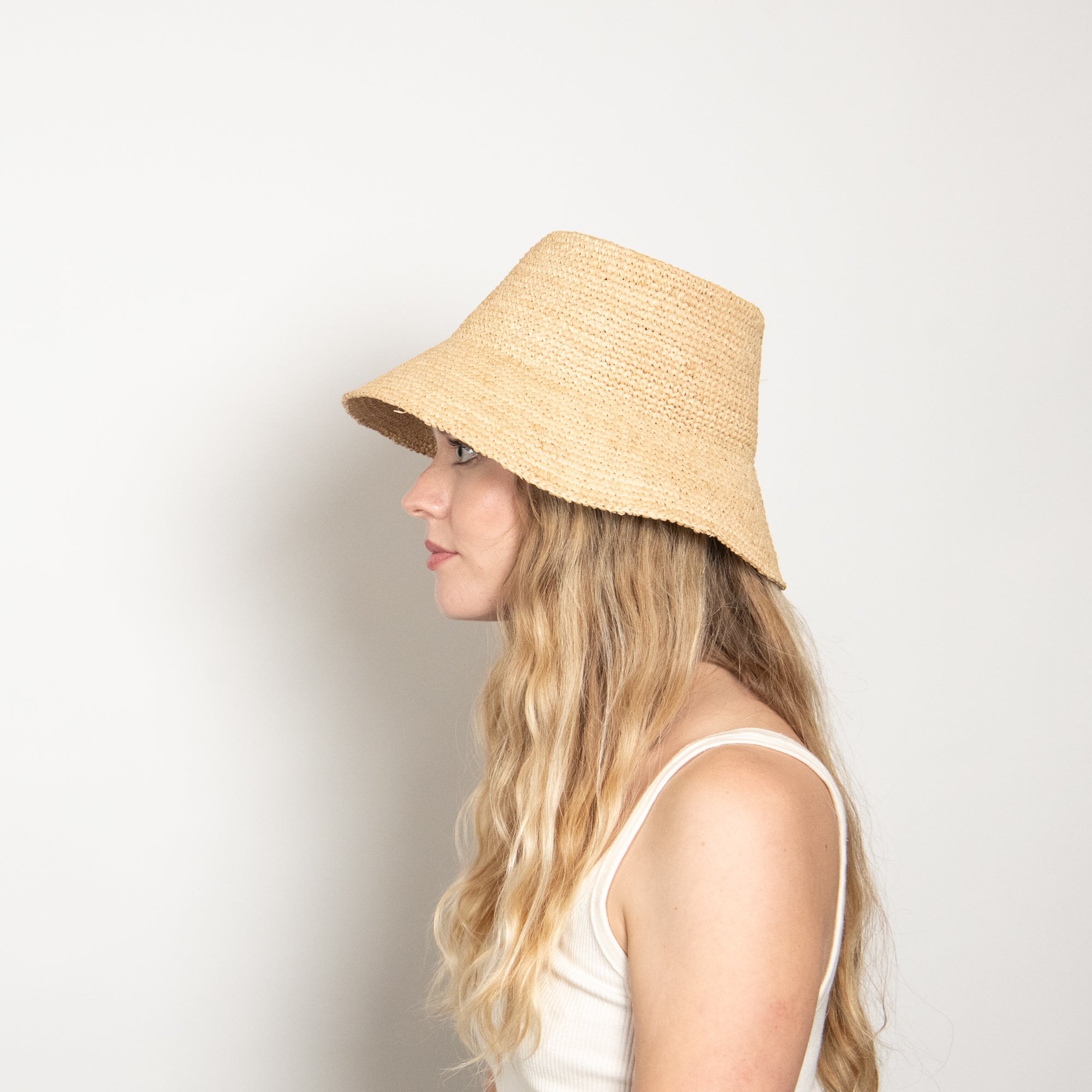 Woman wearing a straw bucket hat against a plain background