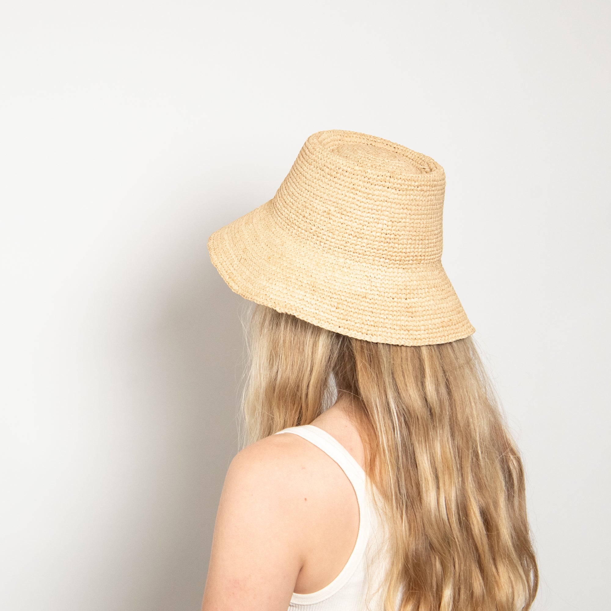 Person wearing a beige bucket hat against a plain background