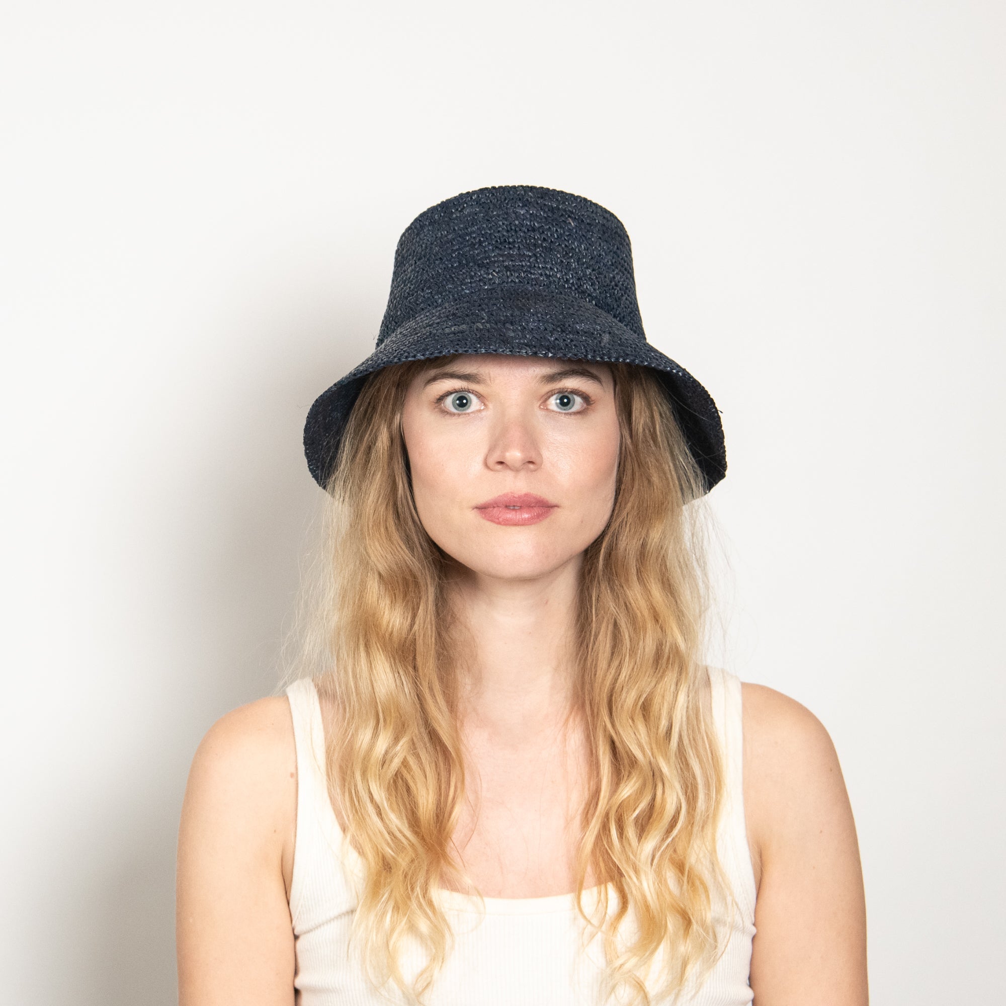 Woman wearing a navy bucket hat against a plain background
