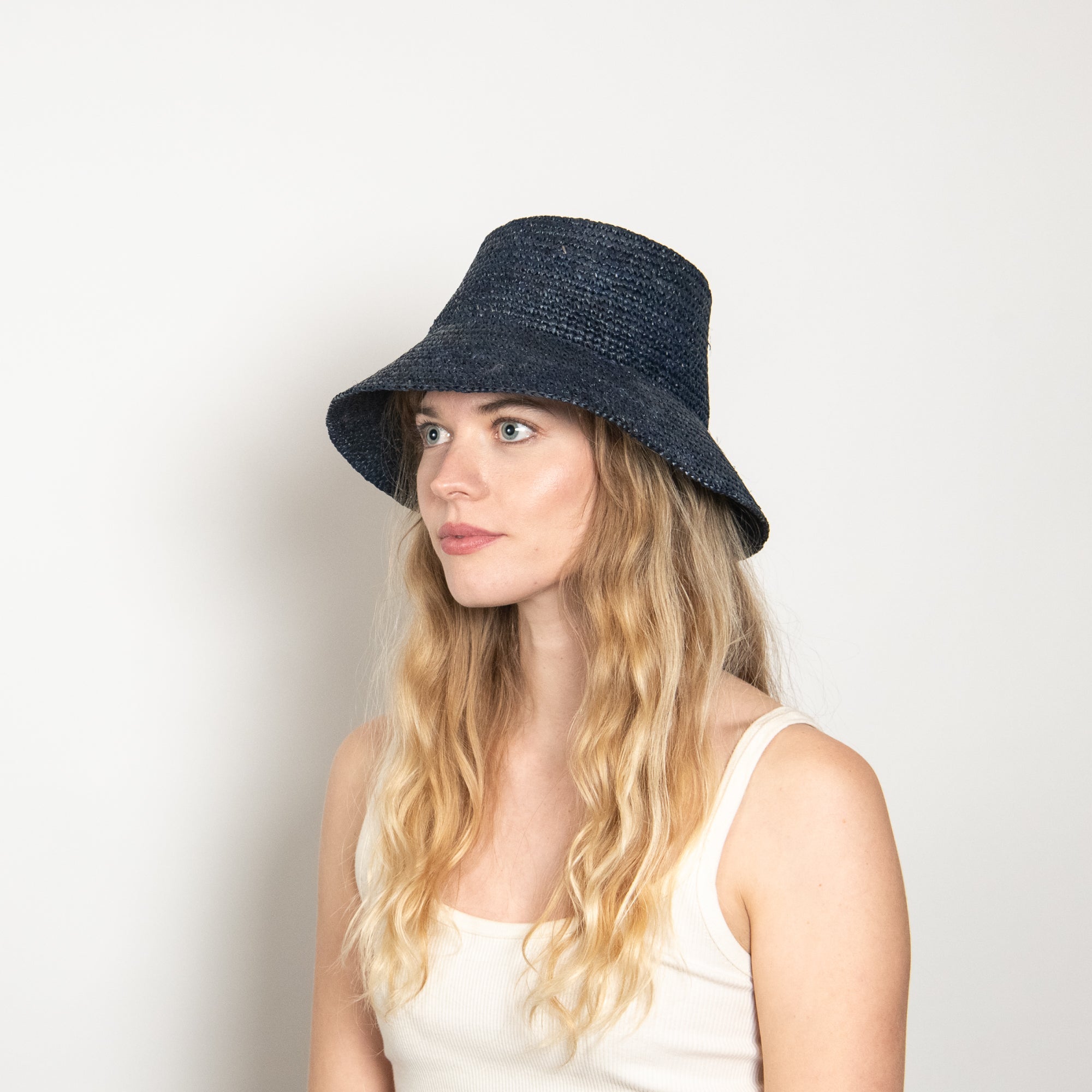 Woman wearing a navy bucket hat against a white background