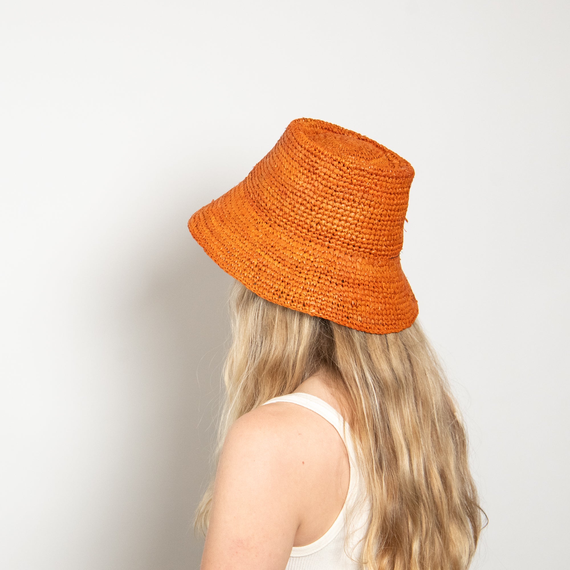 Person wearing an orange knitted hat on a plain background