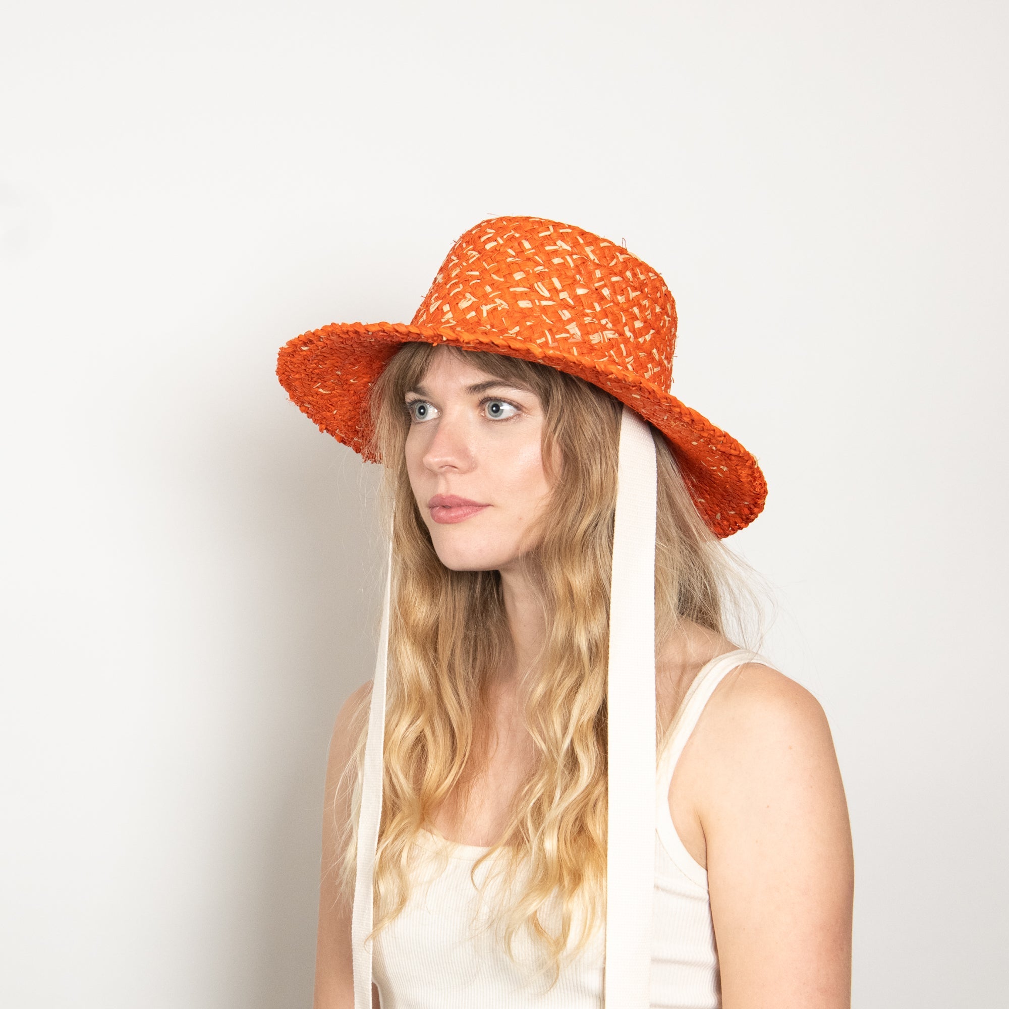 Woman wearing an orange straw hat with a white background