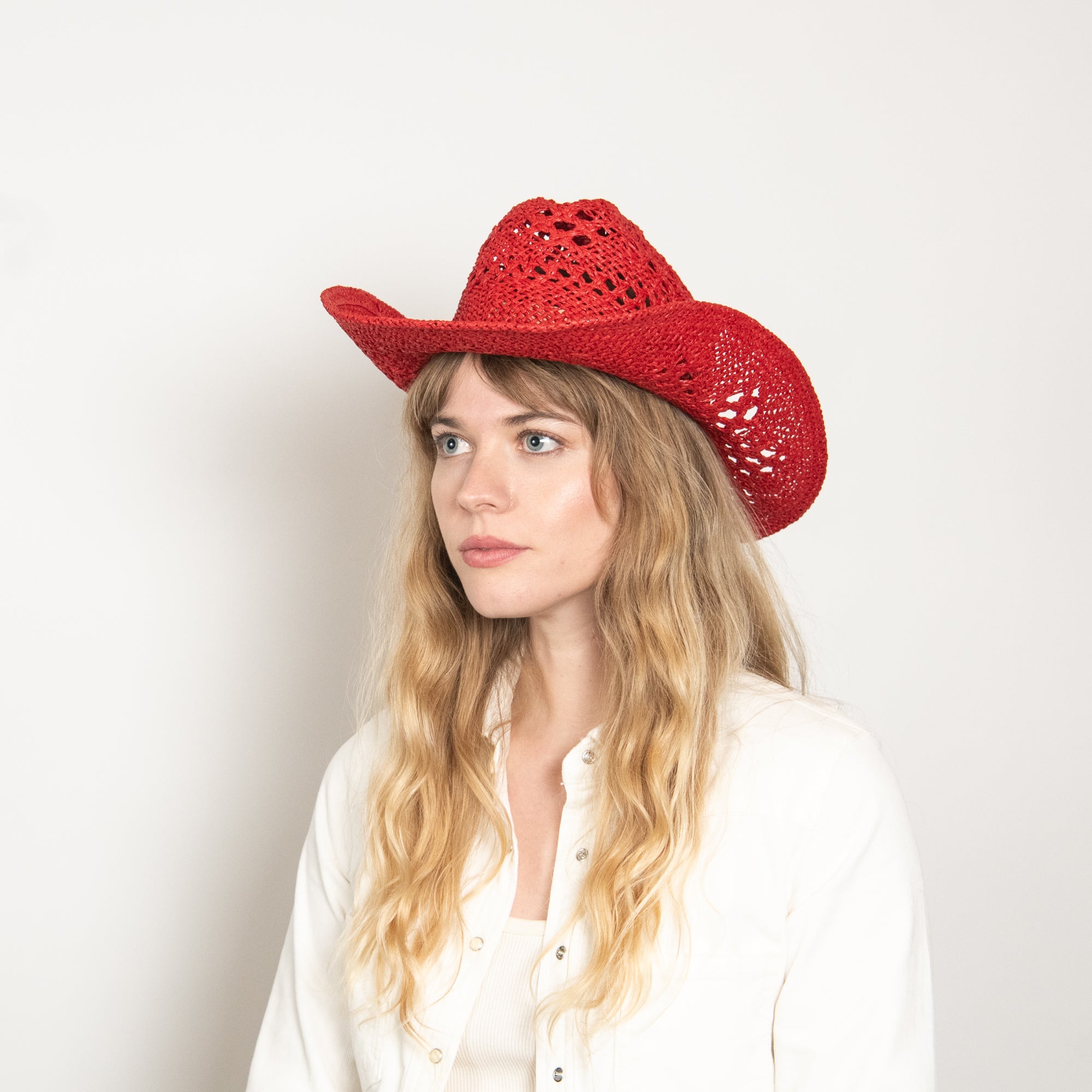 Woman wearing a red cowboy hat against a plain background