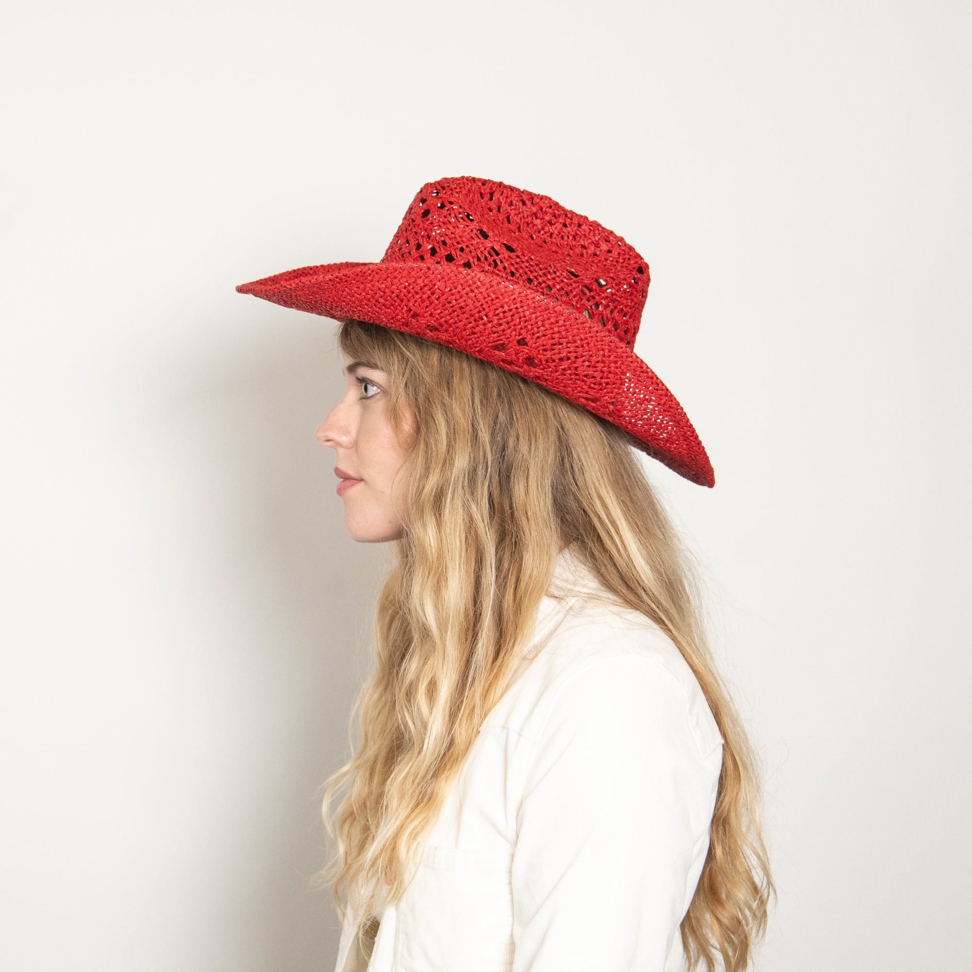 Woman wearing a red straw hat against a plain background