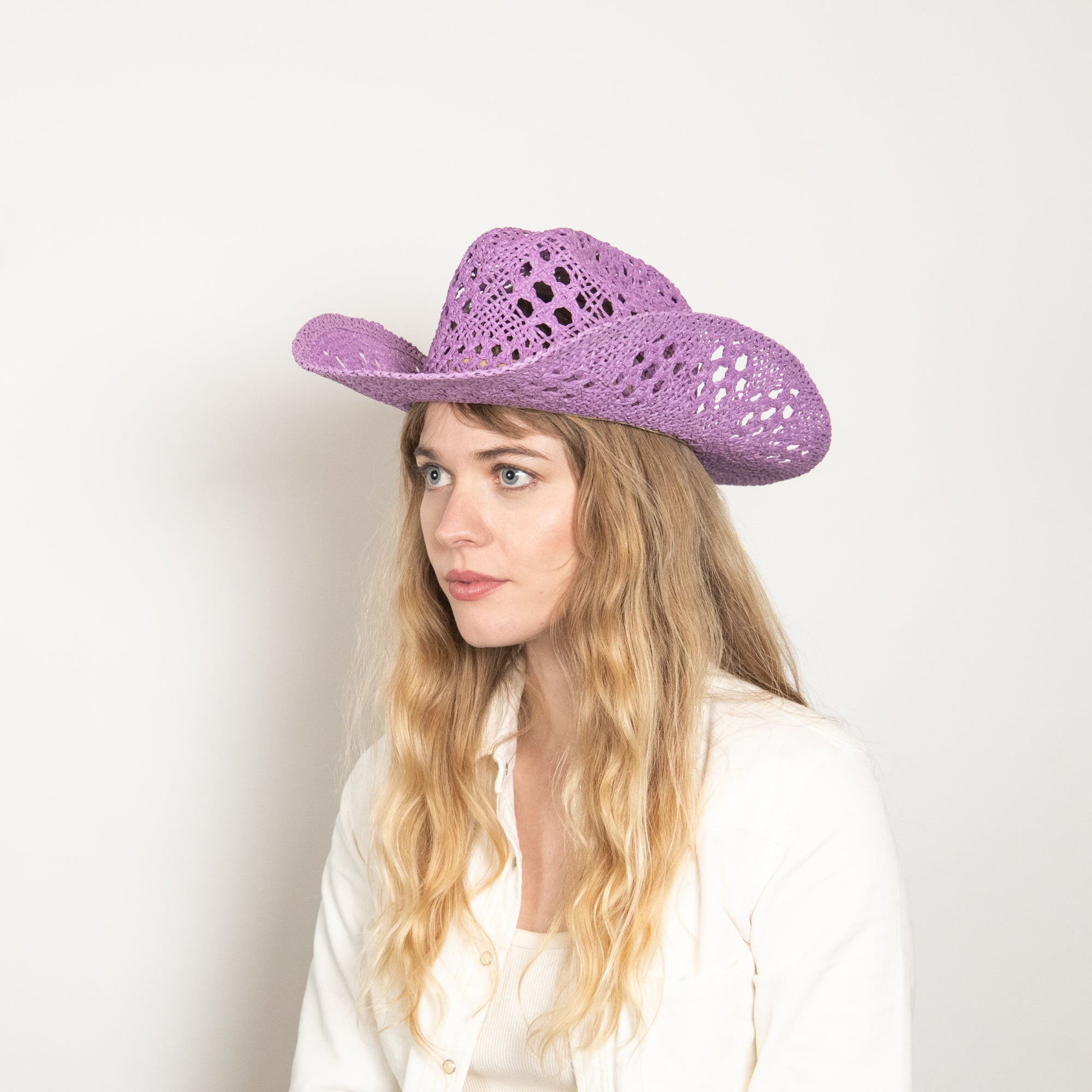 Woman wearing a purple cowboy hat against a white background