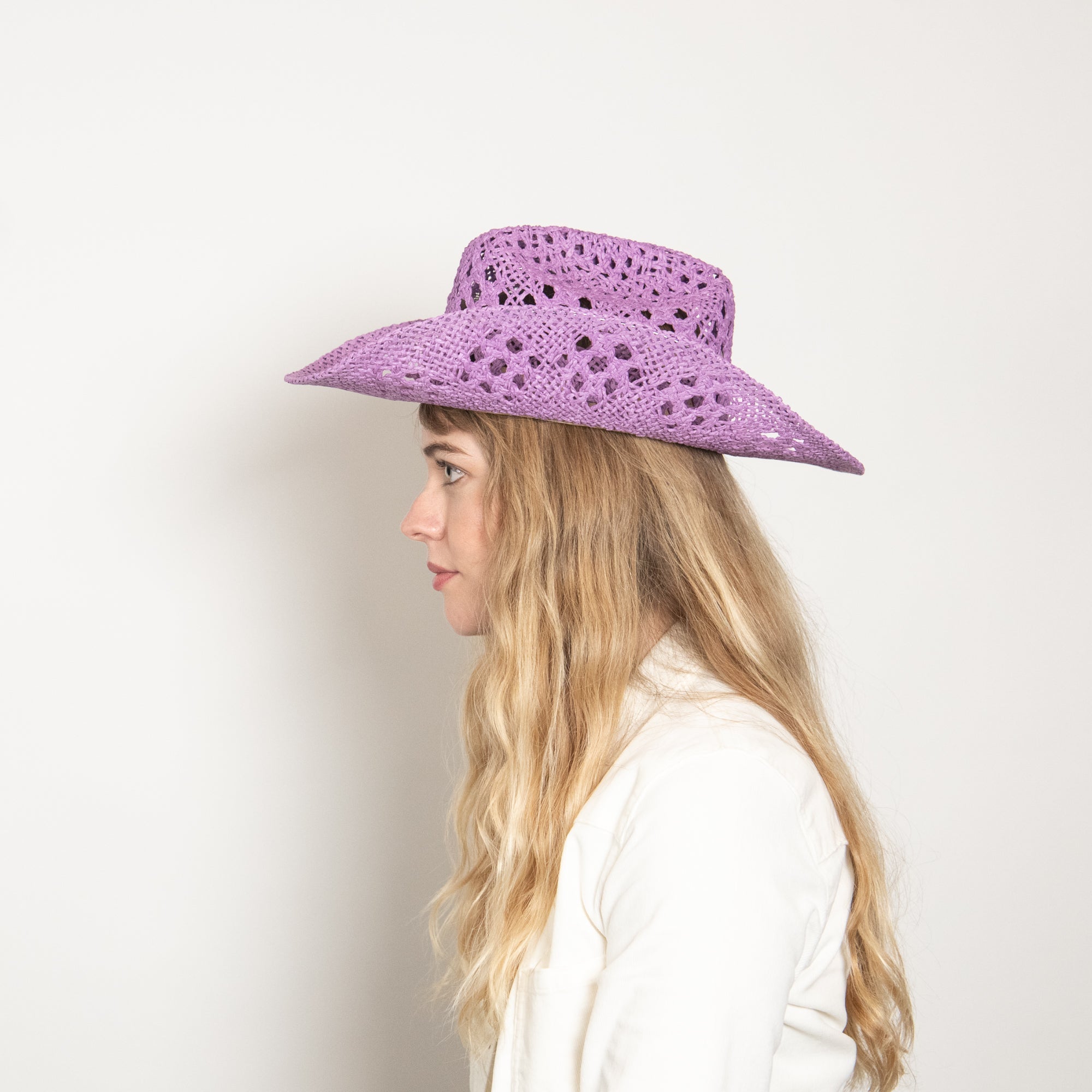 Woman wearing a purple sun hat against a white background