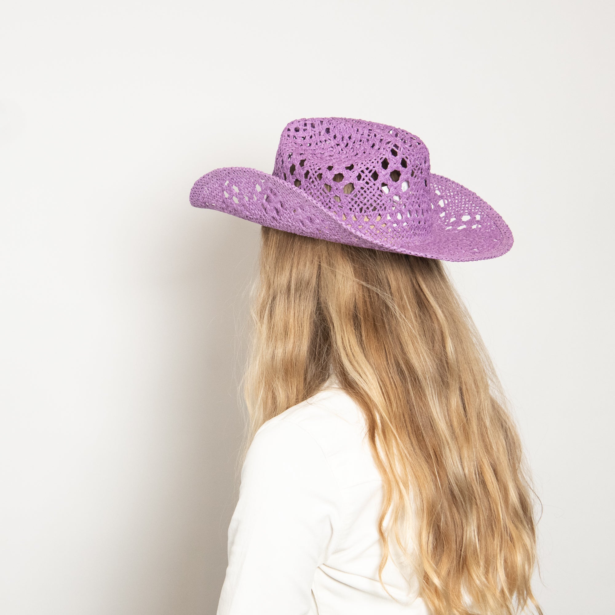 Person wearing a purple straw hat against a white background