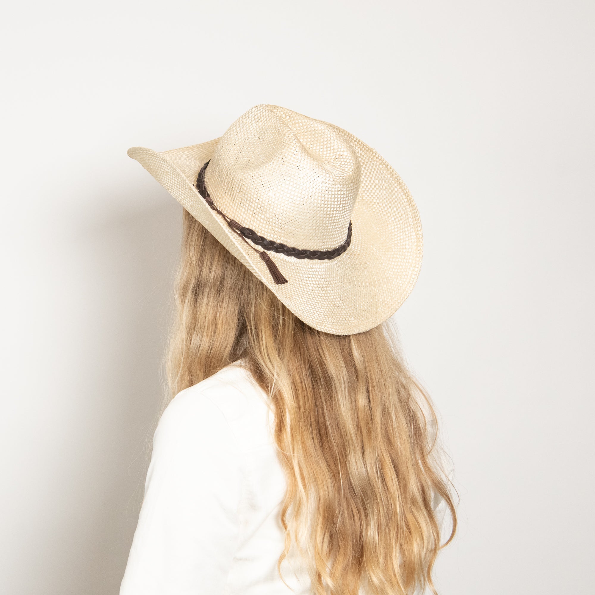 Person wearing a straw hat with a black band on a plain background