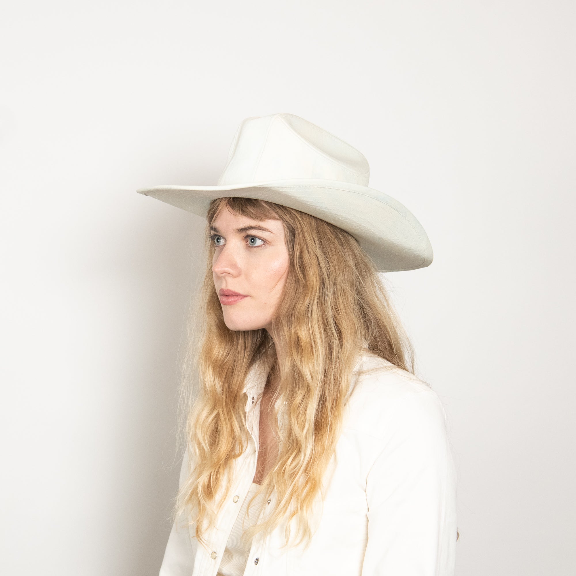 Woman wearing a white hat against a plain background