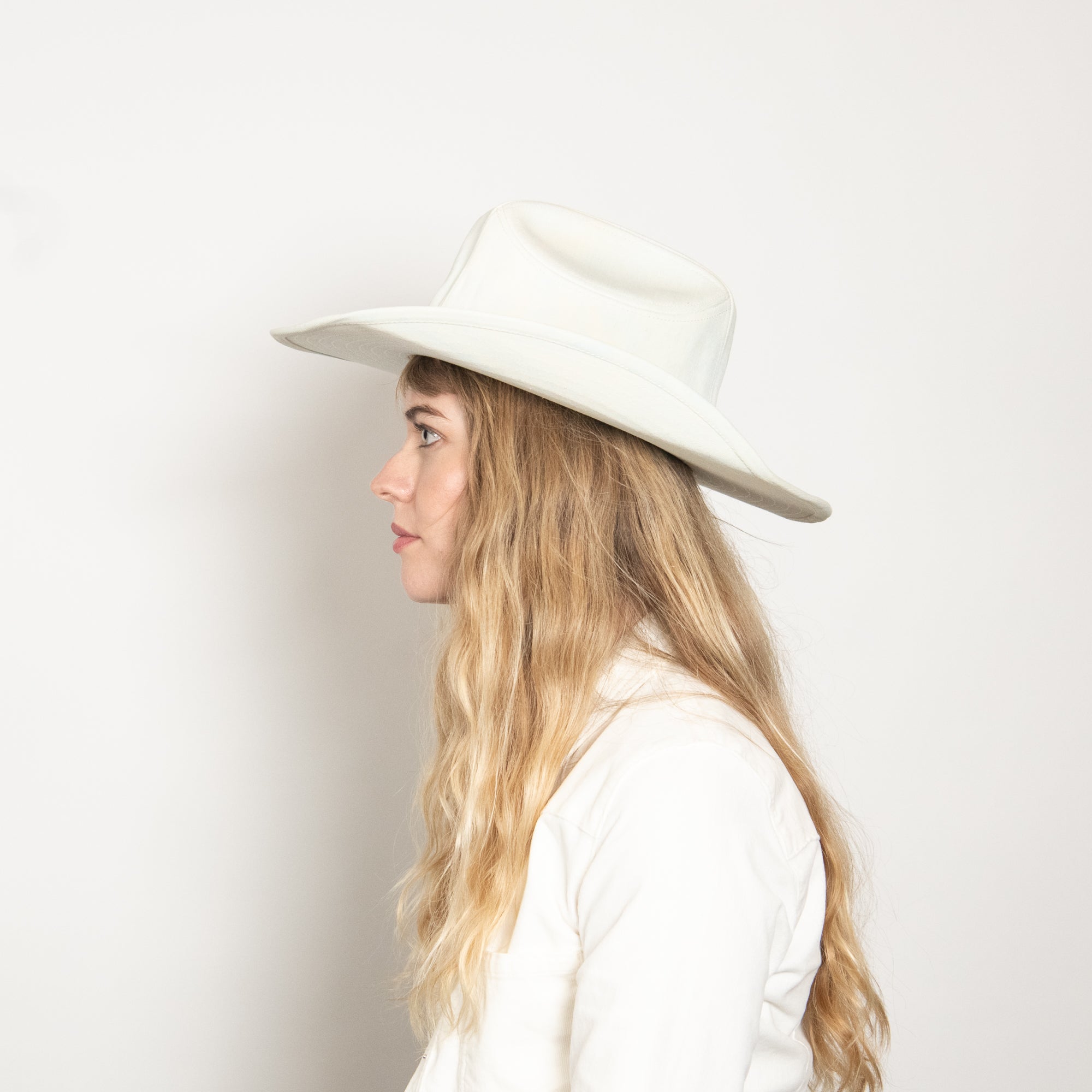 Woman wearing a white hat against a plain background