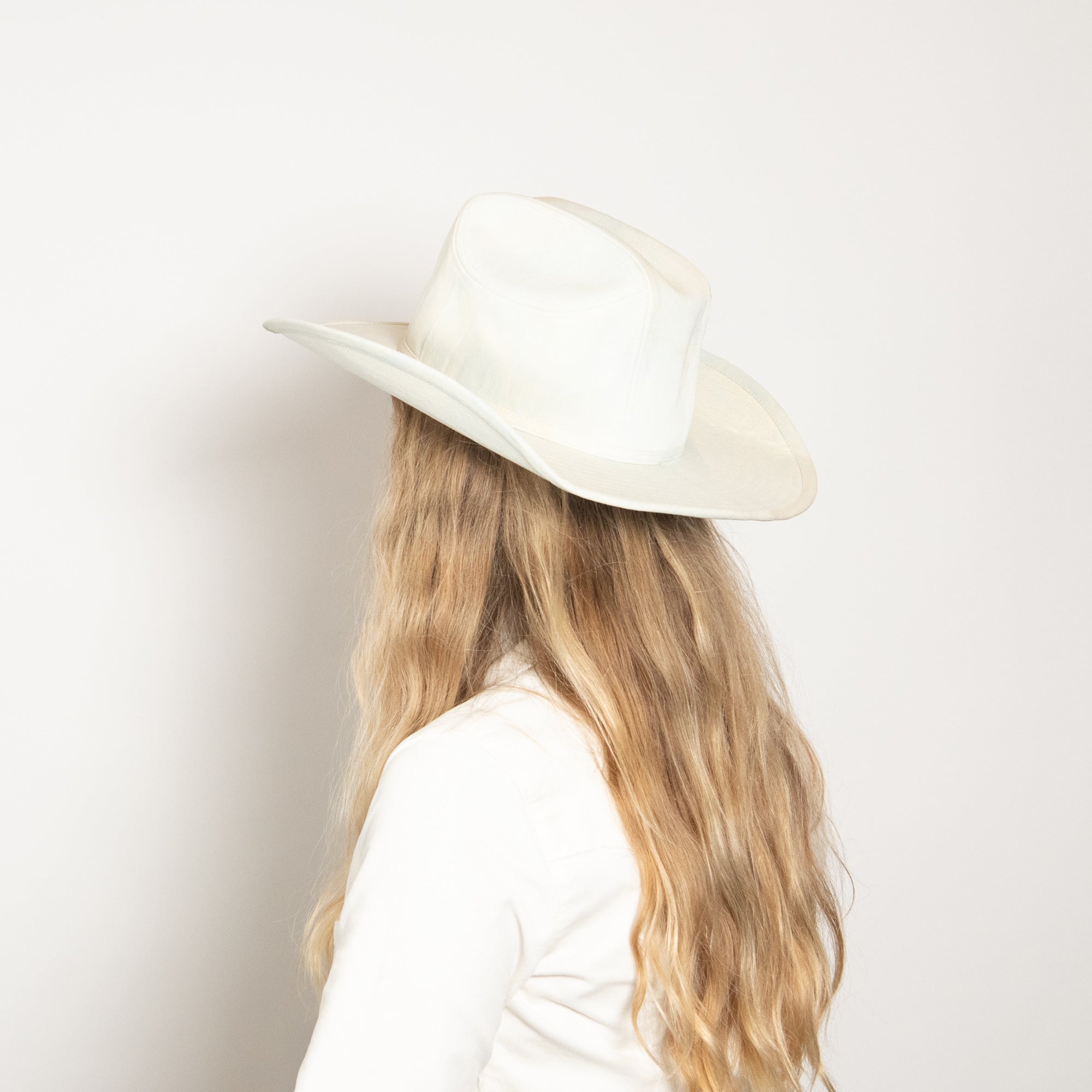 Person wearing a white hat and white shirt against a light background
