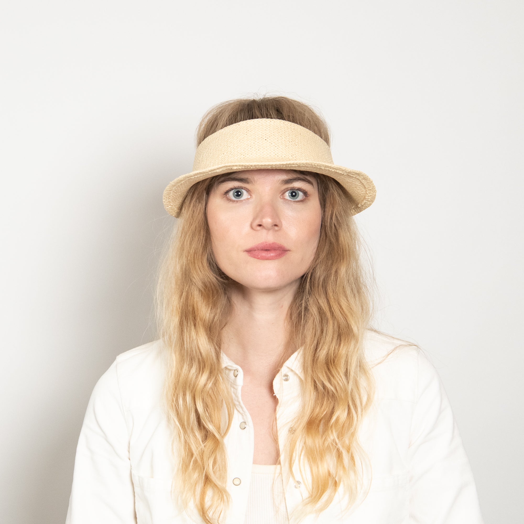 Woman wearing a beige visor against a plain background