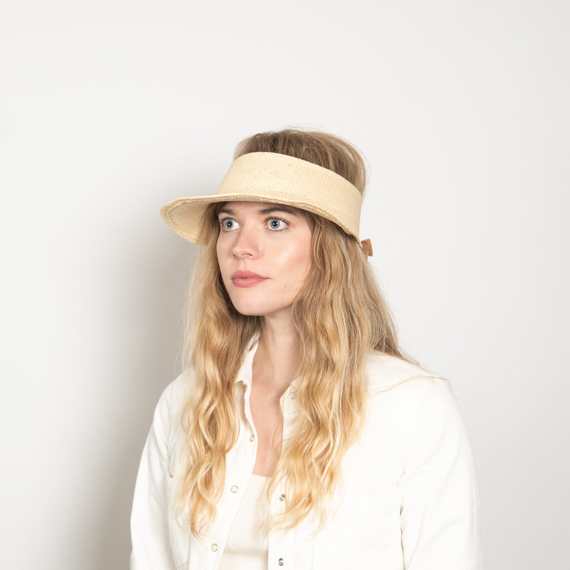Woman wearing a beige visor against a plain background