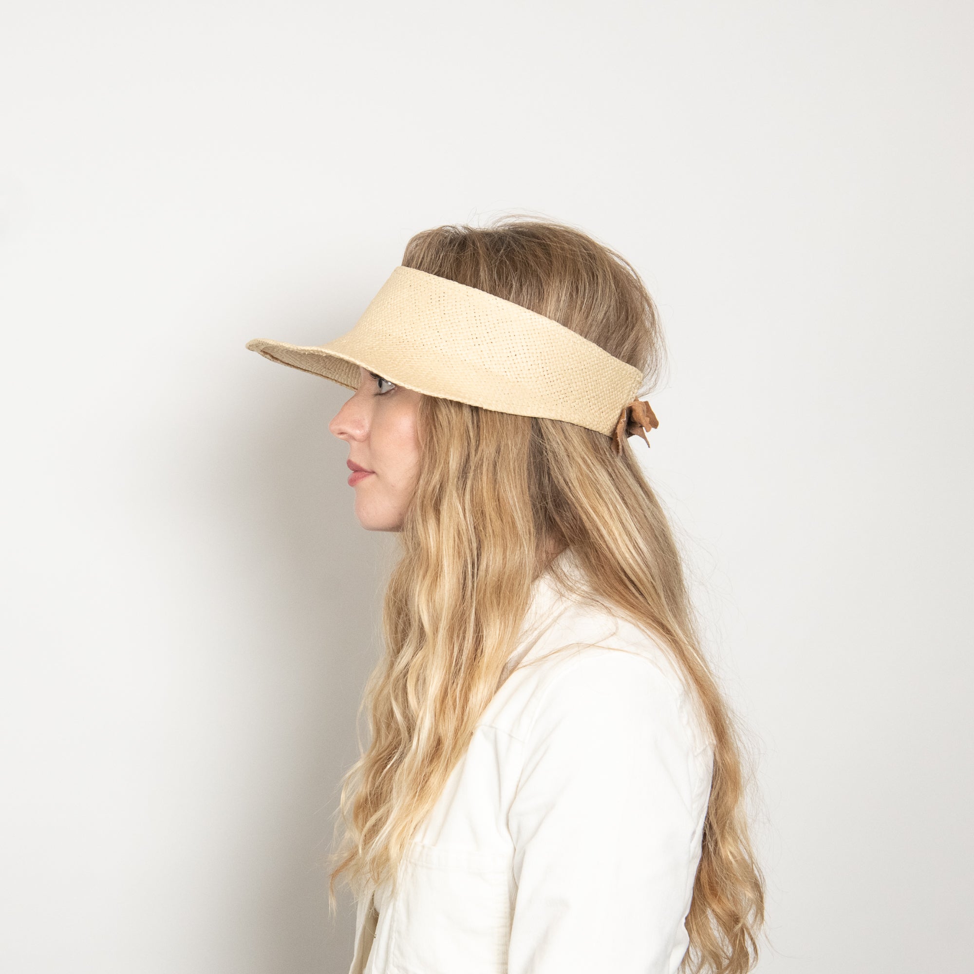 Woman wearing a beige visor against a plain background