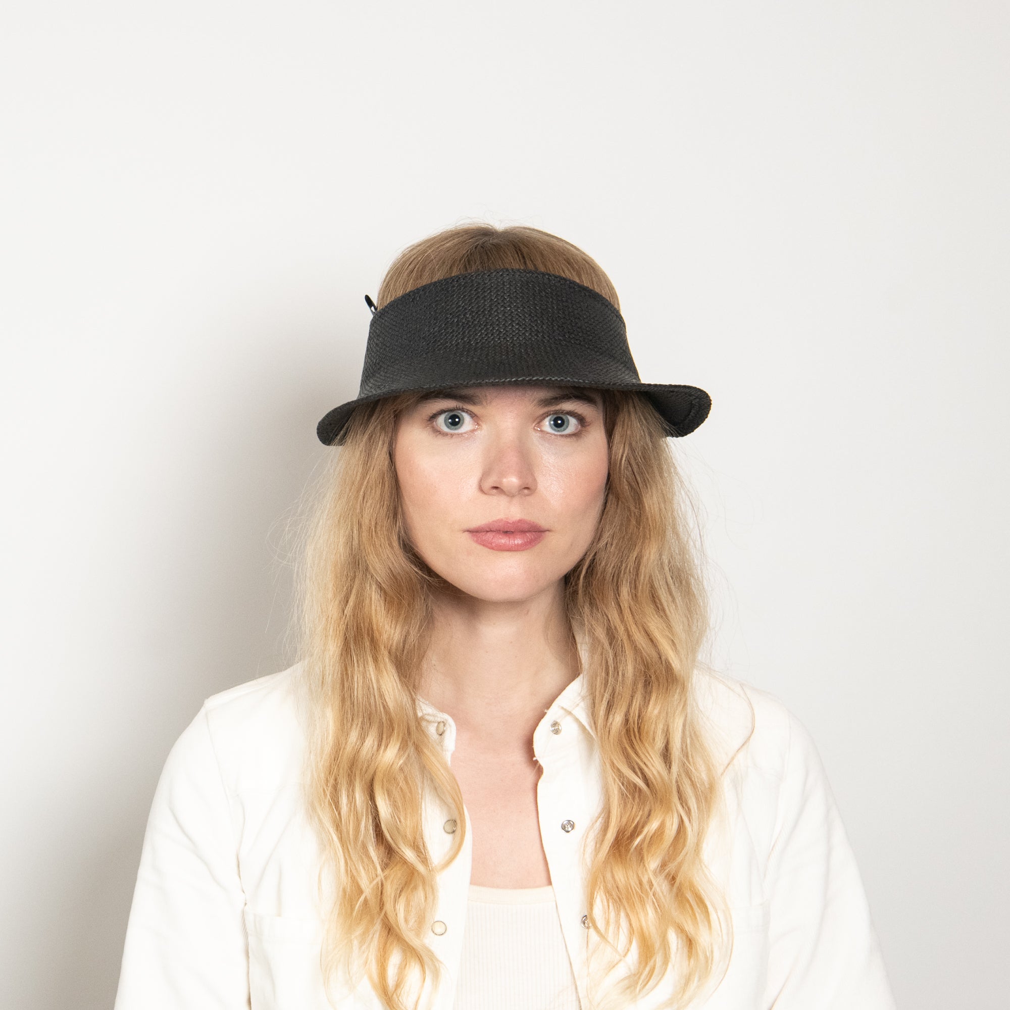 Woman wearing a black visor hat against a plain background
