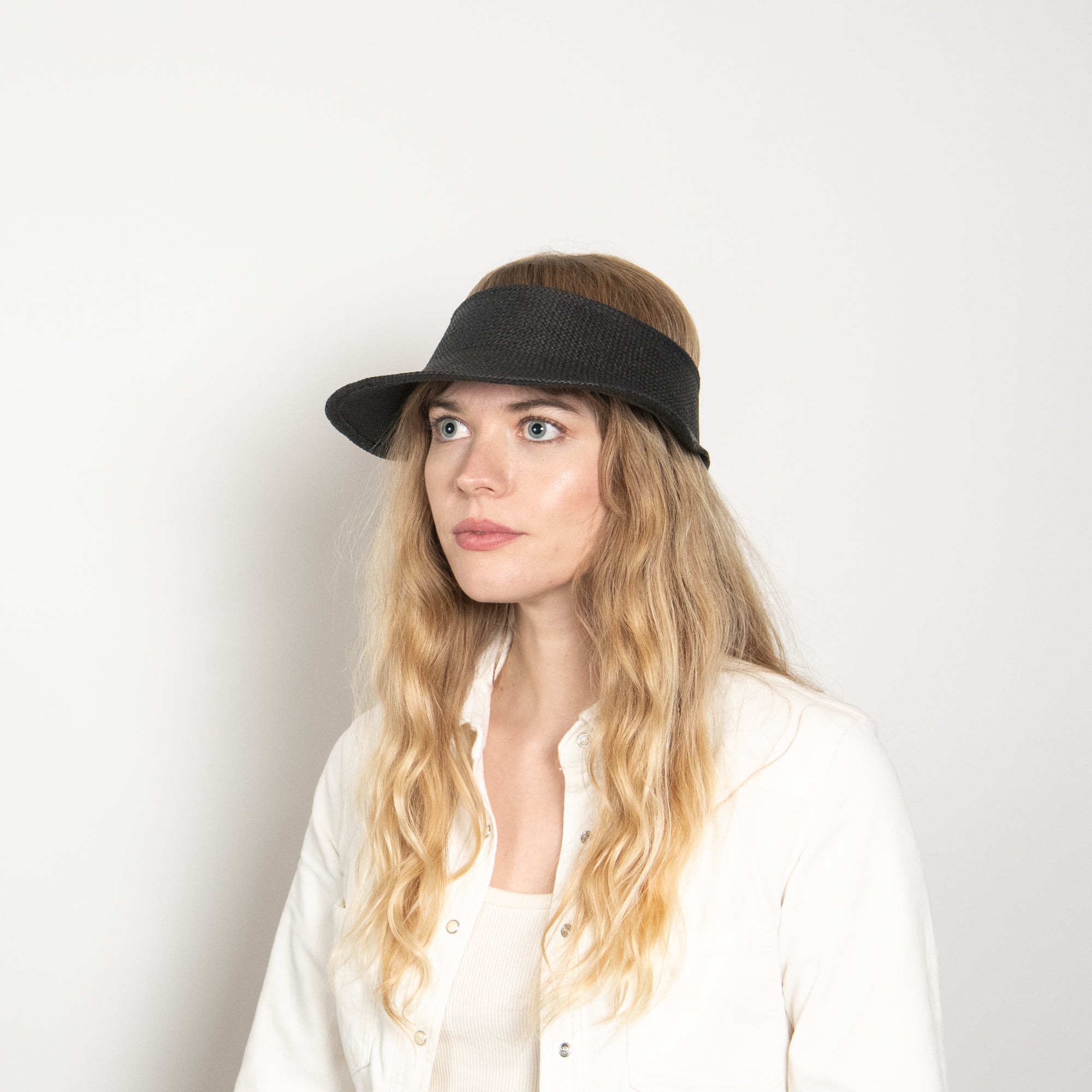 Woman wearing a black visor against a white background