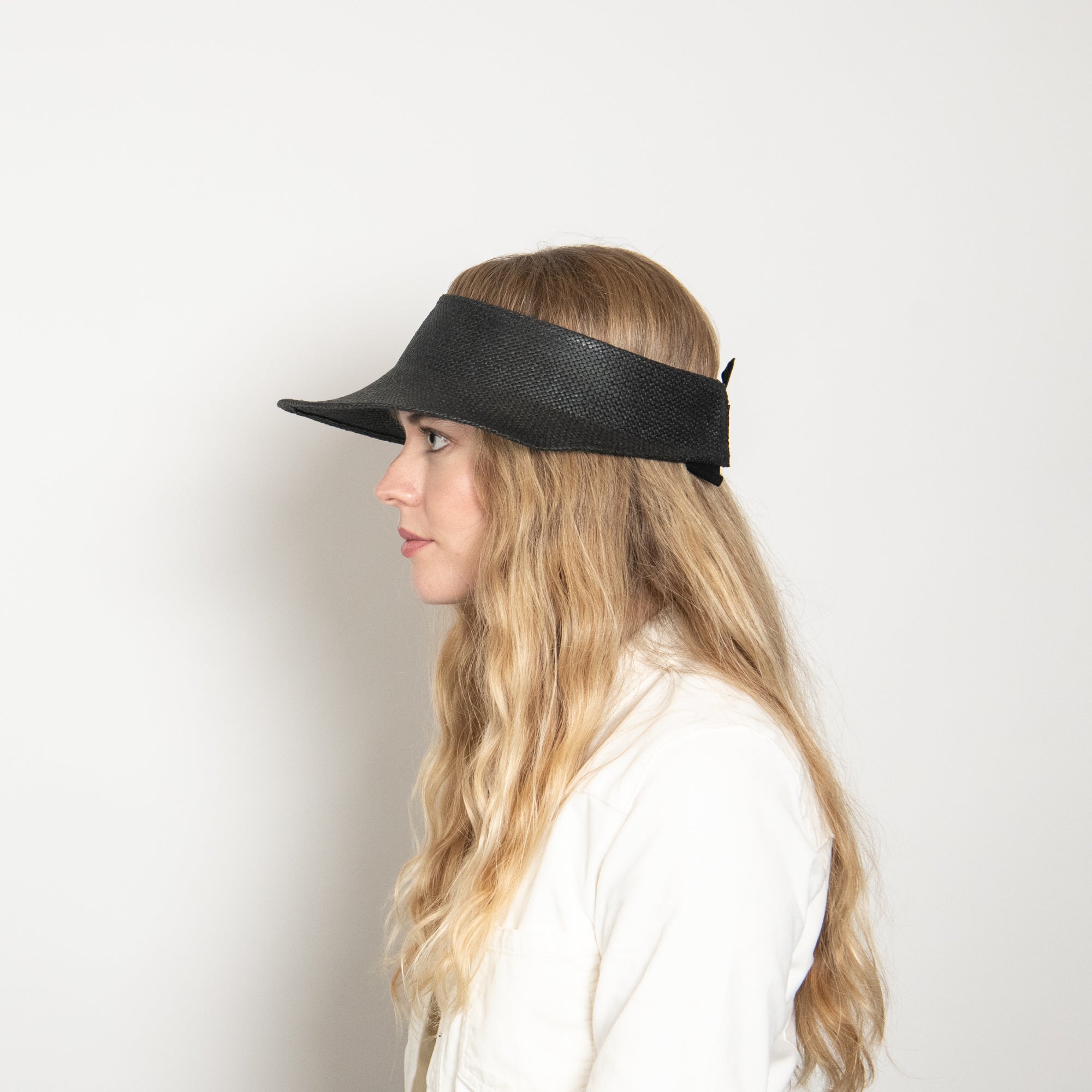 Woman wearing a black visor against a plain background