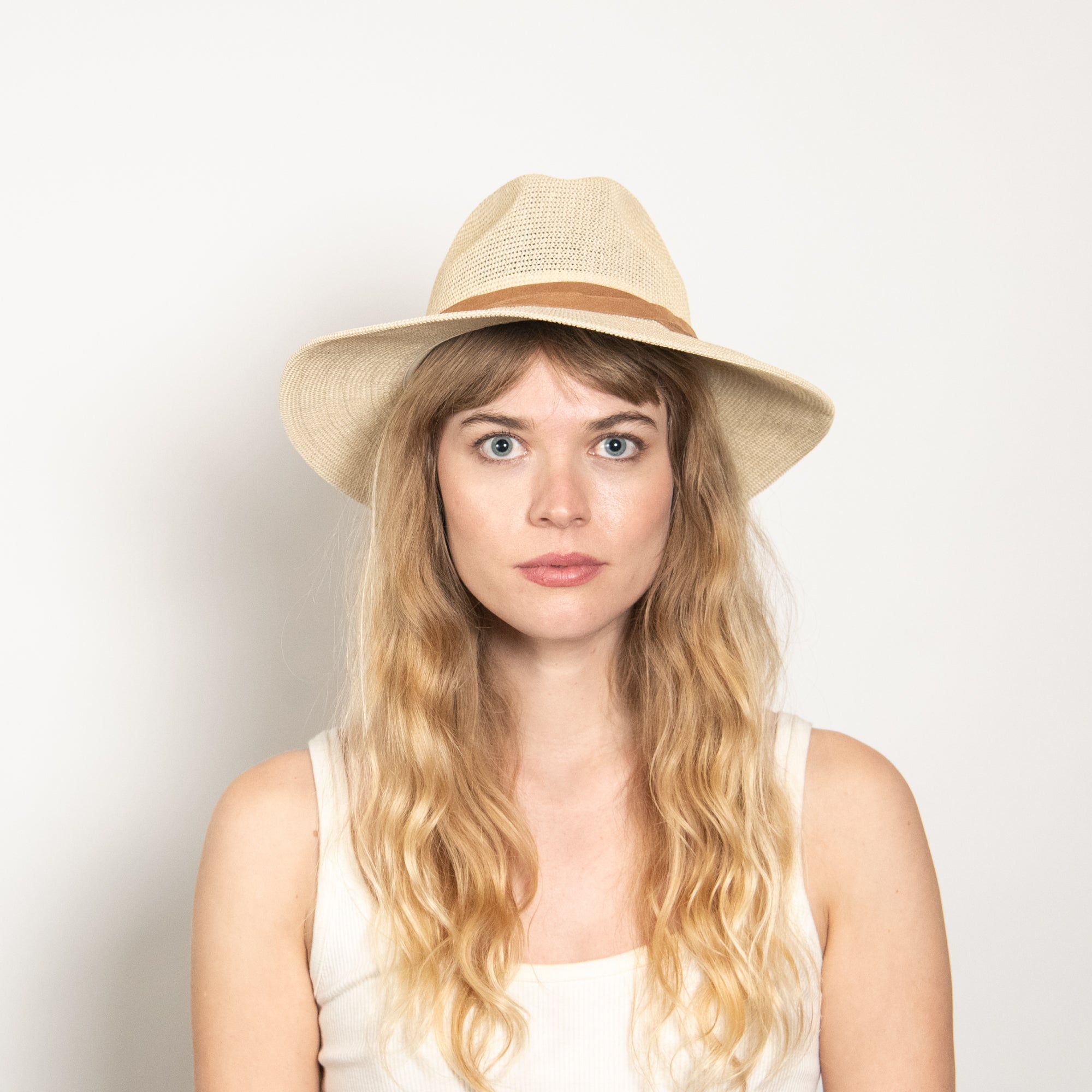 Woman wearing a beige hat against a plain background