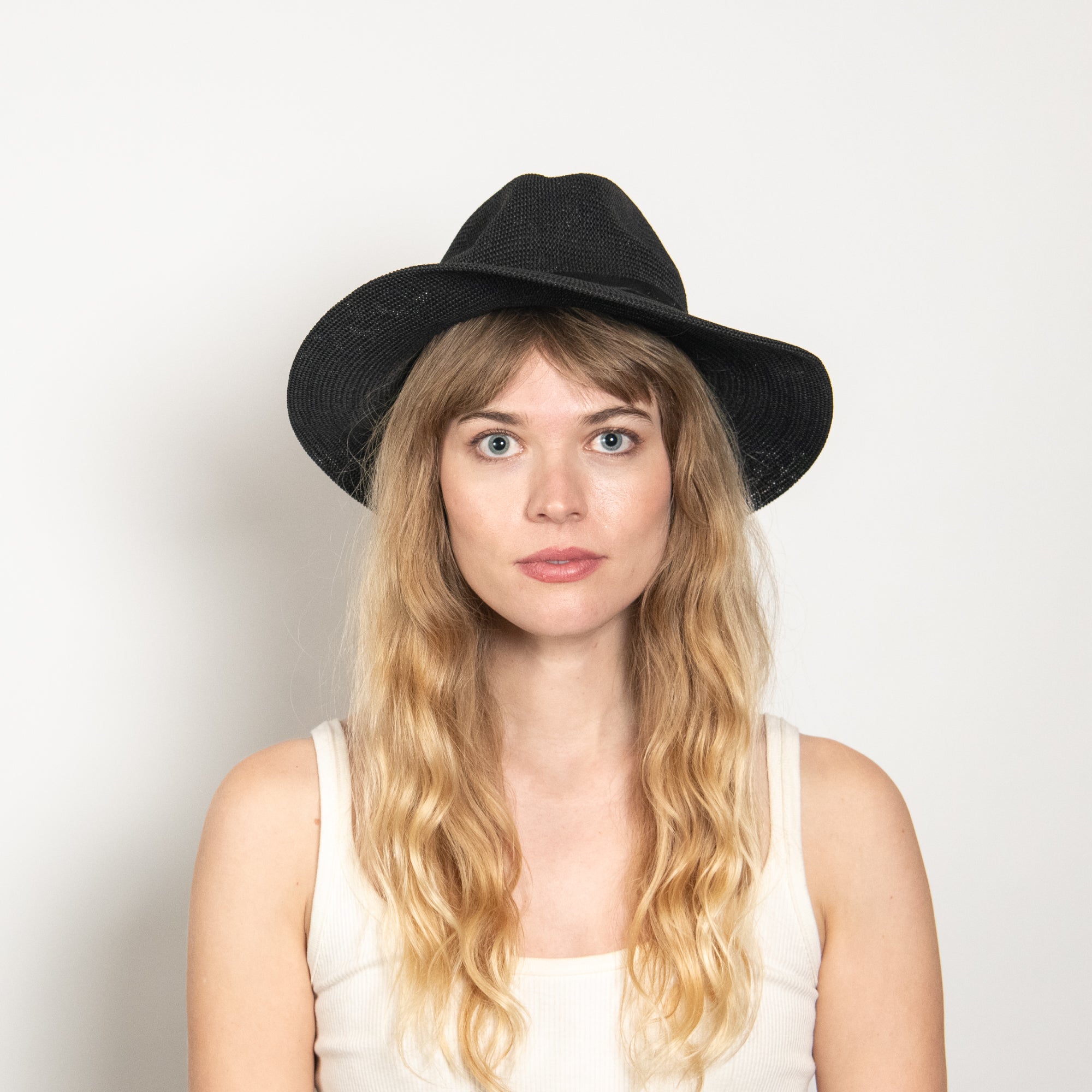 Woman wearing a black hat against a plain background