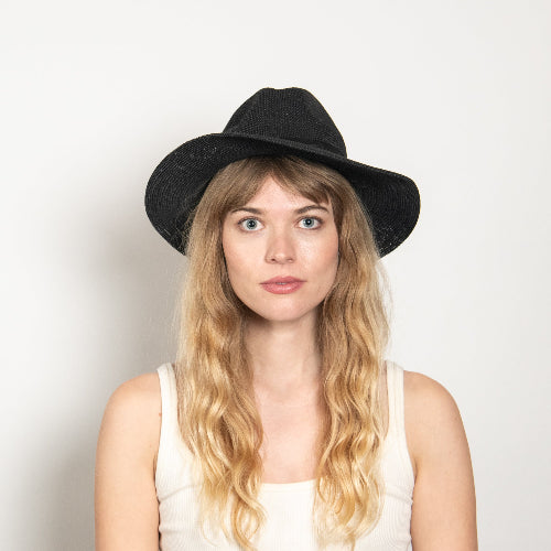 Woman wearing a black hat against a plain background